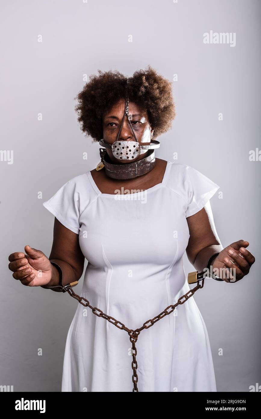 Portrait d'une femme noire dans les chaînes avec un masque de fer sur sa bouche. L'esclavage au Brésil. Bras dans la prière. Reproduction en studio. Banque D'Images