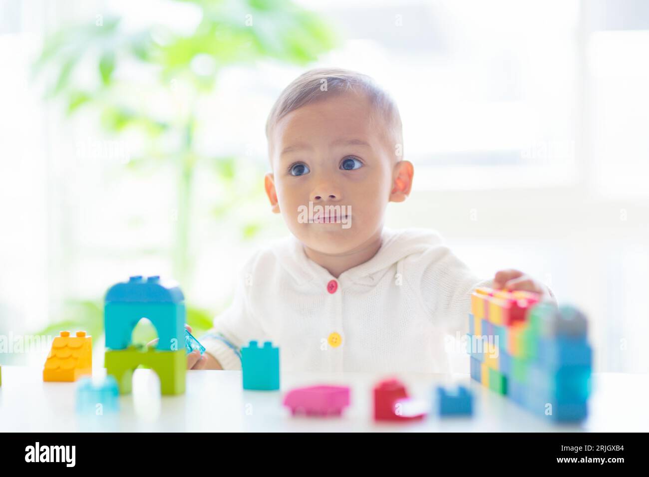 Adorable bébé asiatique jouant avec des blocs colorés jouet dans la chambre blanche ensoleillée. Bébé mignon avec des jouets éducatifs. Tour de bâtiment pour enfants. Développement précoce Banque D'Images