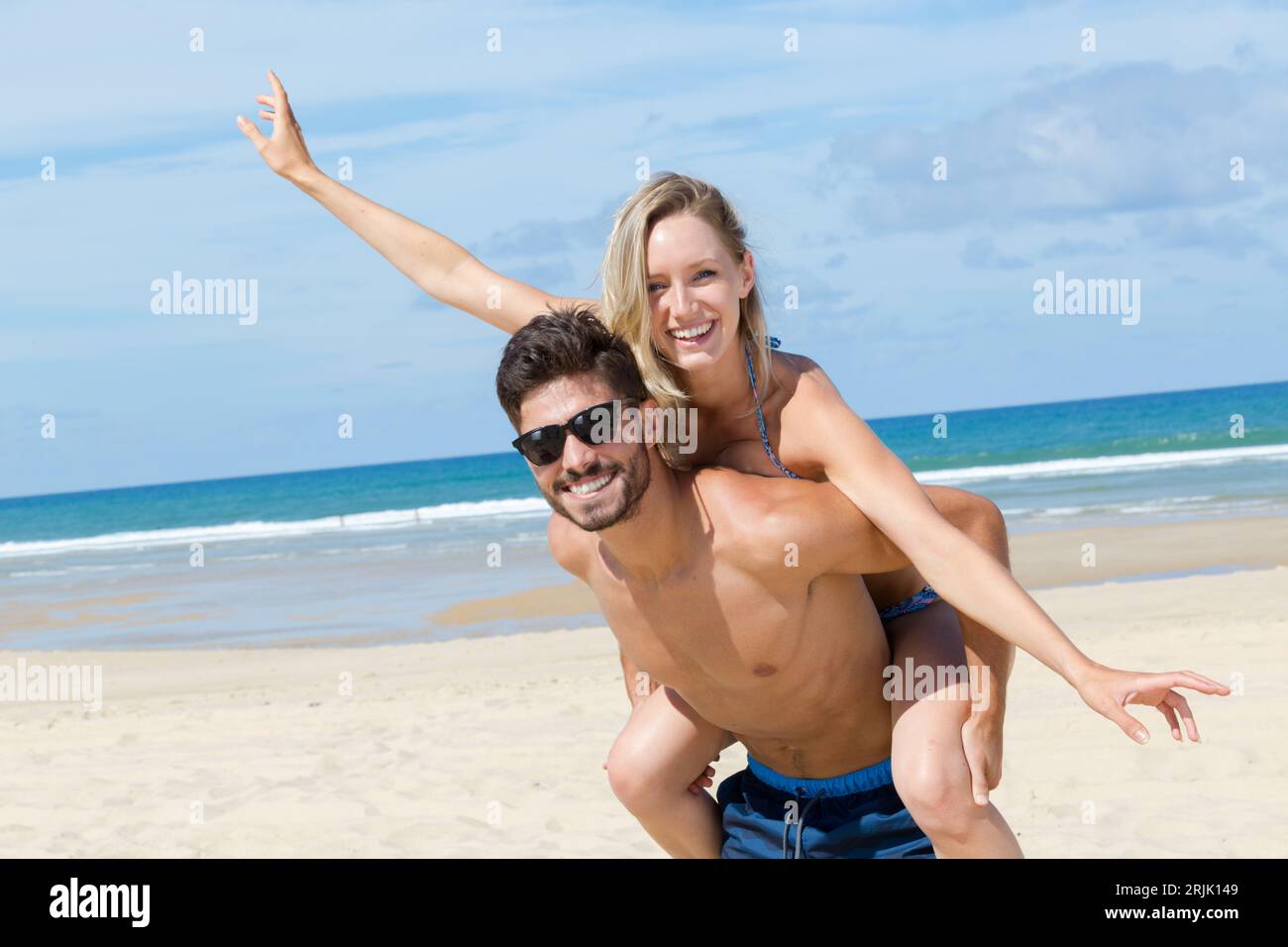 un jeune couple se fait une balade à dos de porc à la plage Banque D'Images
