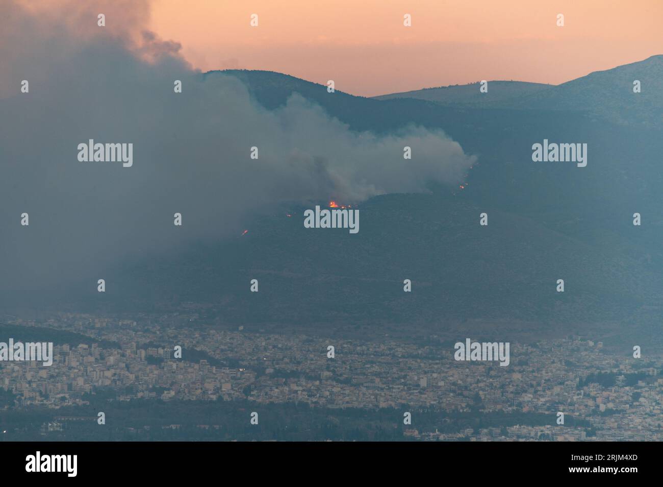 Le 22/08/2023 un feu de forêt a commencé sur les contreforts de la montagne Parnitha dans la banlieue ouest d'Athènes, Grèce. Alimentée par des vents violents, elle a rapidement grandi et brûlé des maisons et des commerces. Cette photo est de Lycabette colline dans le centre d'Athènes regardant vers la montagne. Banque D'Images