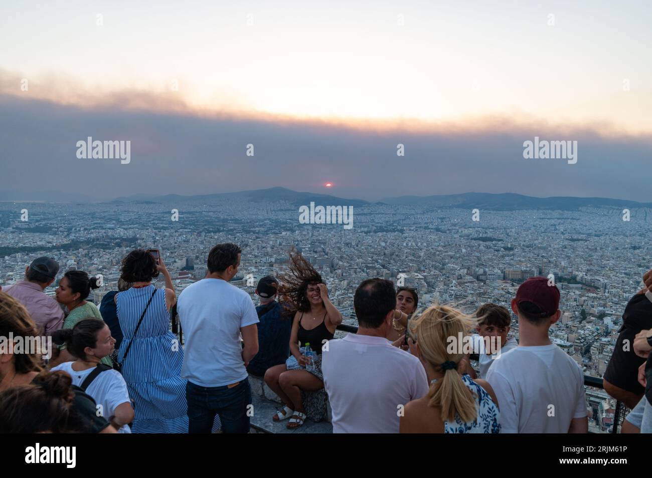 Le 22/08/2023 un feu de forêt a commencé sur les contreforts de la montagne Parnitha dans la banlieue ouest d'Athènes, Grèce. Alimentée par des vents violents, elle a rapidement grandi et brûlé des maisons et des commerces. Cette photo est de la colline de Lycabette, où les touristes et les habitants regardent le feu. Banque D'Images