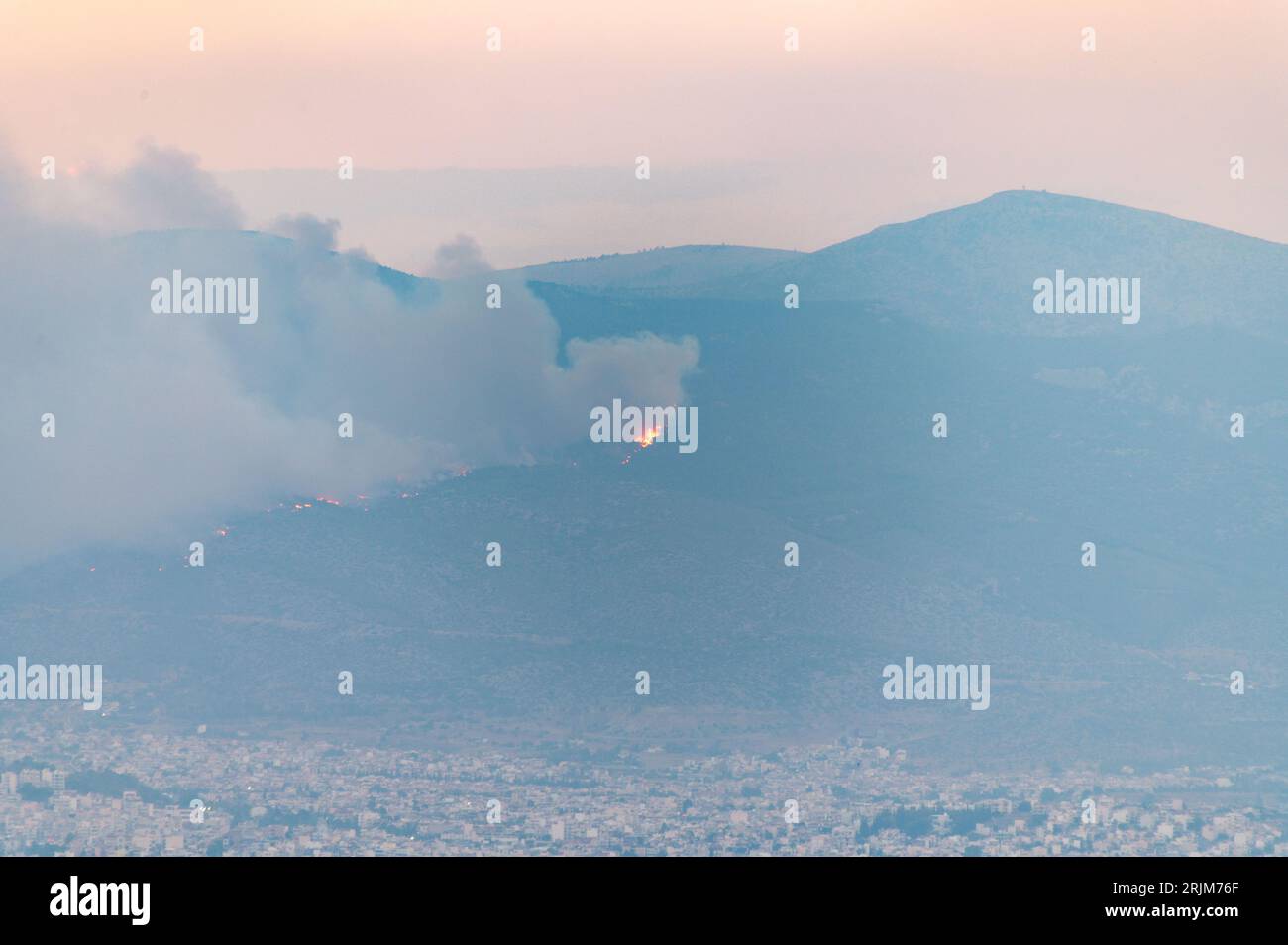 Le 22/08/2023 un feu de forêt a commencé sur les contreforts de la montagne Parnitha dans la banlieue ouest d'Athènes, Grèce. Alimentée par des vents violents, elle a rapidement grandi et brûlé des maisons et des commerces. Cette photo est de Lycabette colline dans le centre d'Athènes regardant vers la montagne. Banque D'Images