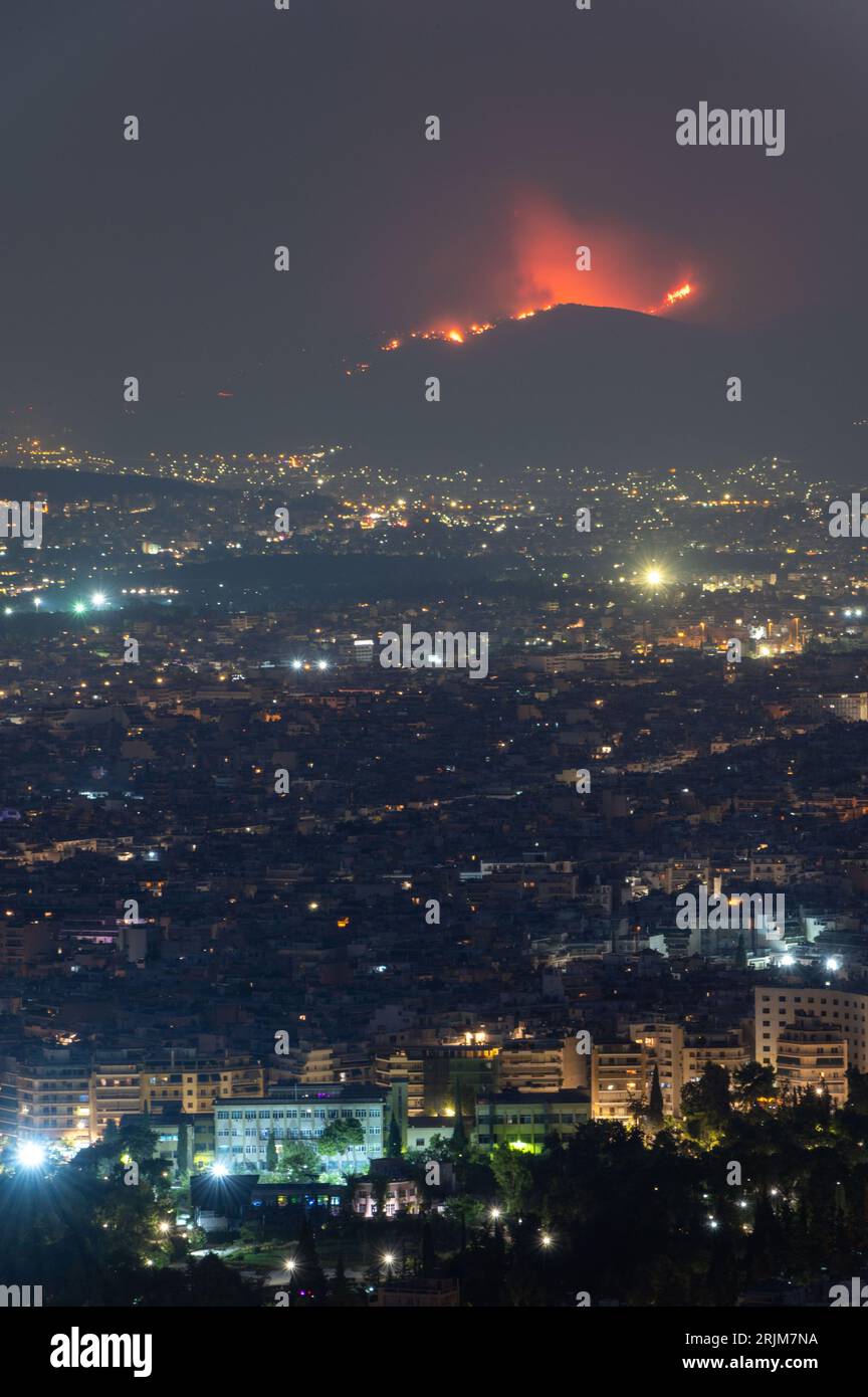 Le 22/08/2023 un feu de forêt a commencé sur les contreforts de la montagne Parnitha dans la banlieue ouest d'Athènes, Grèce. Alimentée par des vents violents, elle a rapidement grandi et brûlé des maisons et des commerces. Cette photo est de la colline de Lycabette la nuit quand le feu brûlait encore. Banque D'Images