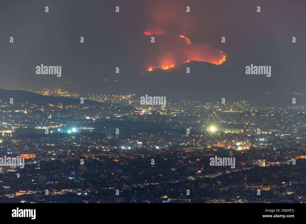 Le 22/08/2023 un feu de forêt a commencé sur les contreforts de la montagne Parnitha dans la banlieue ouest d'Athènes, Grèce. Alimentée par des vents violents, elle a rapidement grandi et brûlé des maisons et des commerces. Cette photo est de Lycabette colline dans le centre d'Athènes regardant vers la montagne. Banque D'Images