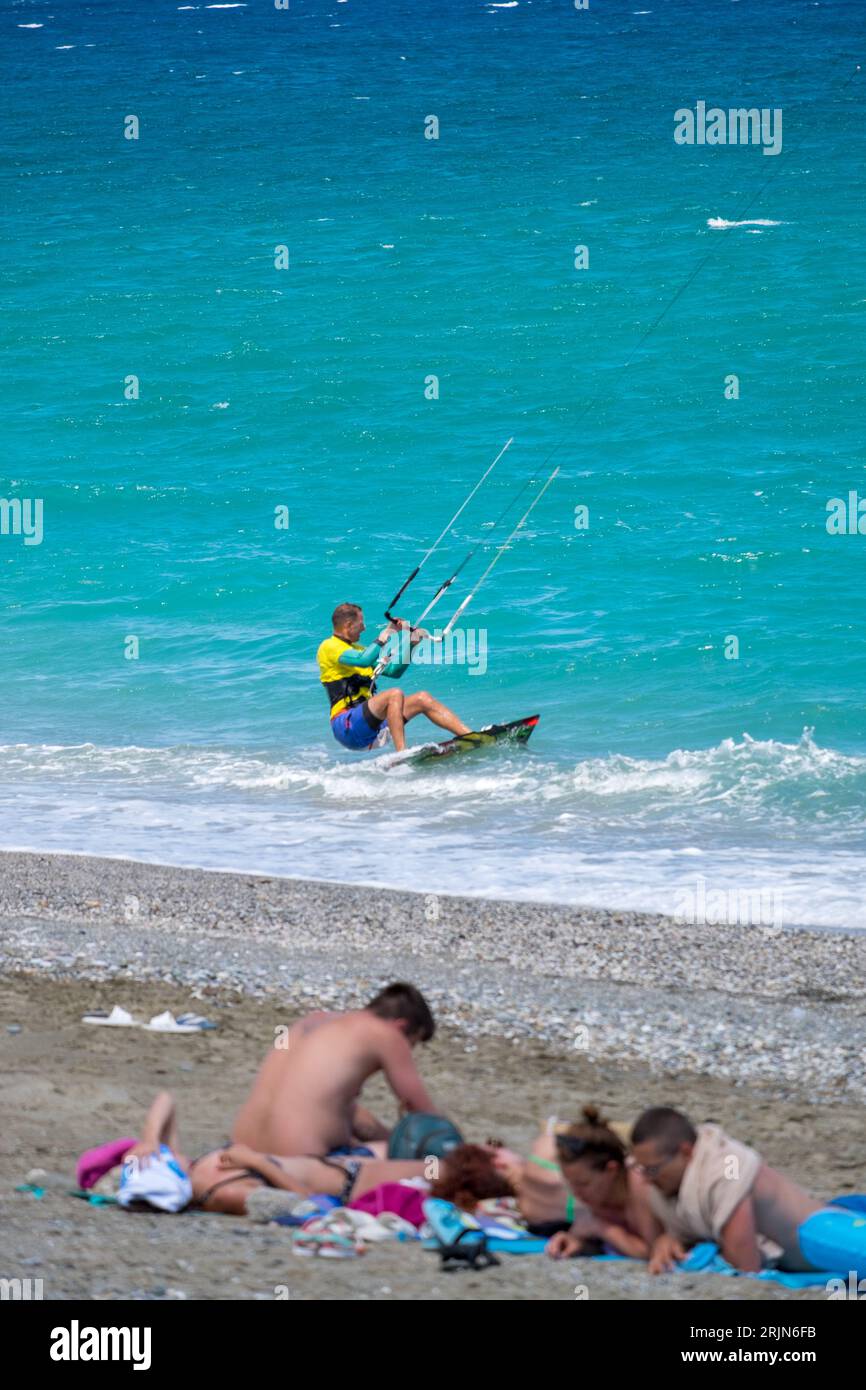 Un homme kite surf devant la plage pleine de gens Banque D'Images