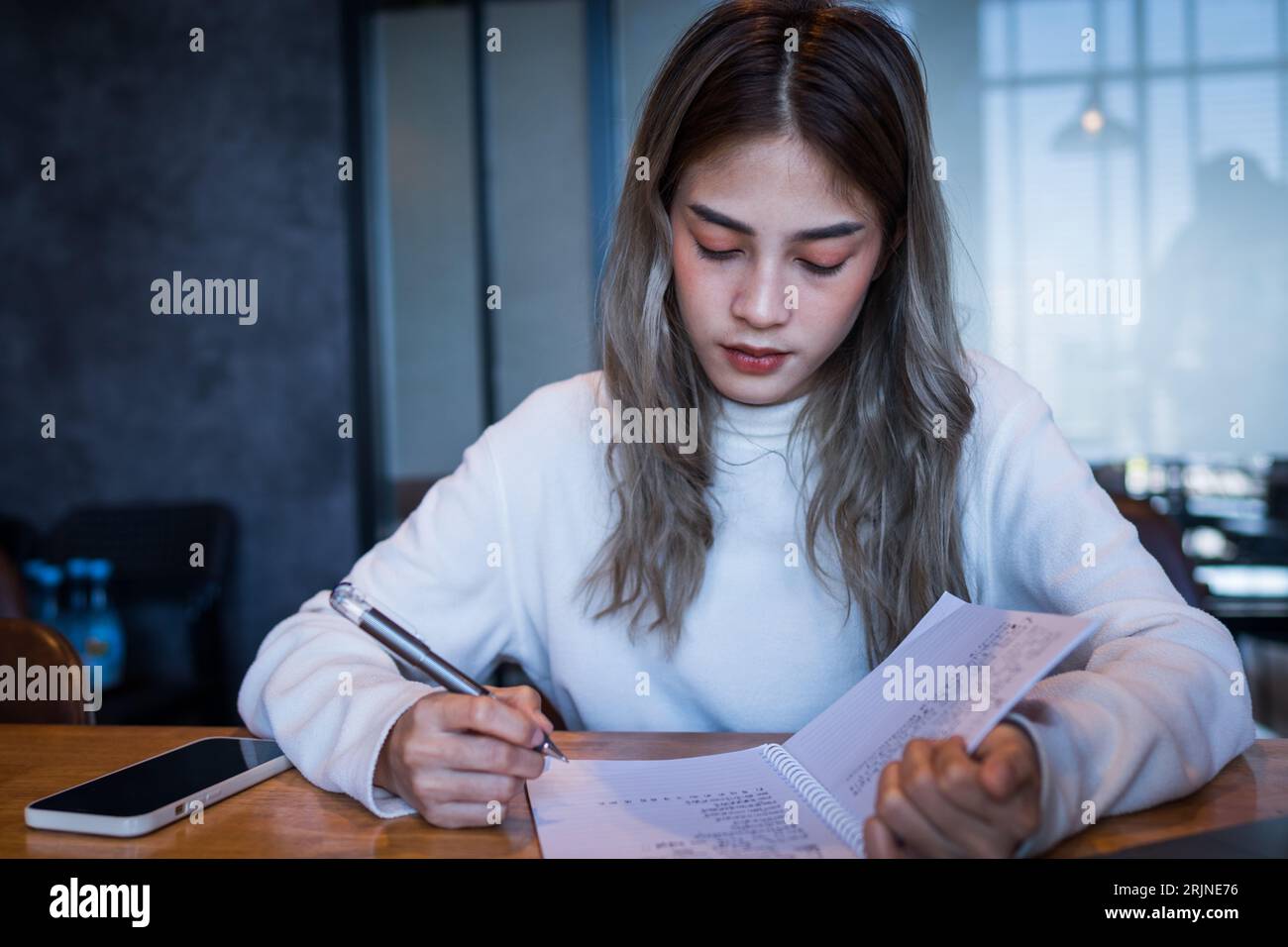Une jeune femme regardant à travers ses notes dans une pièce Banque D'Images
