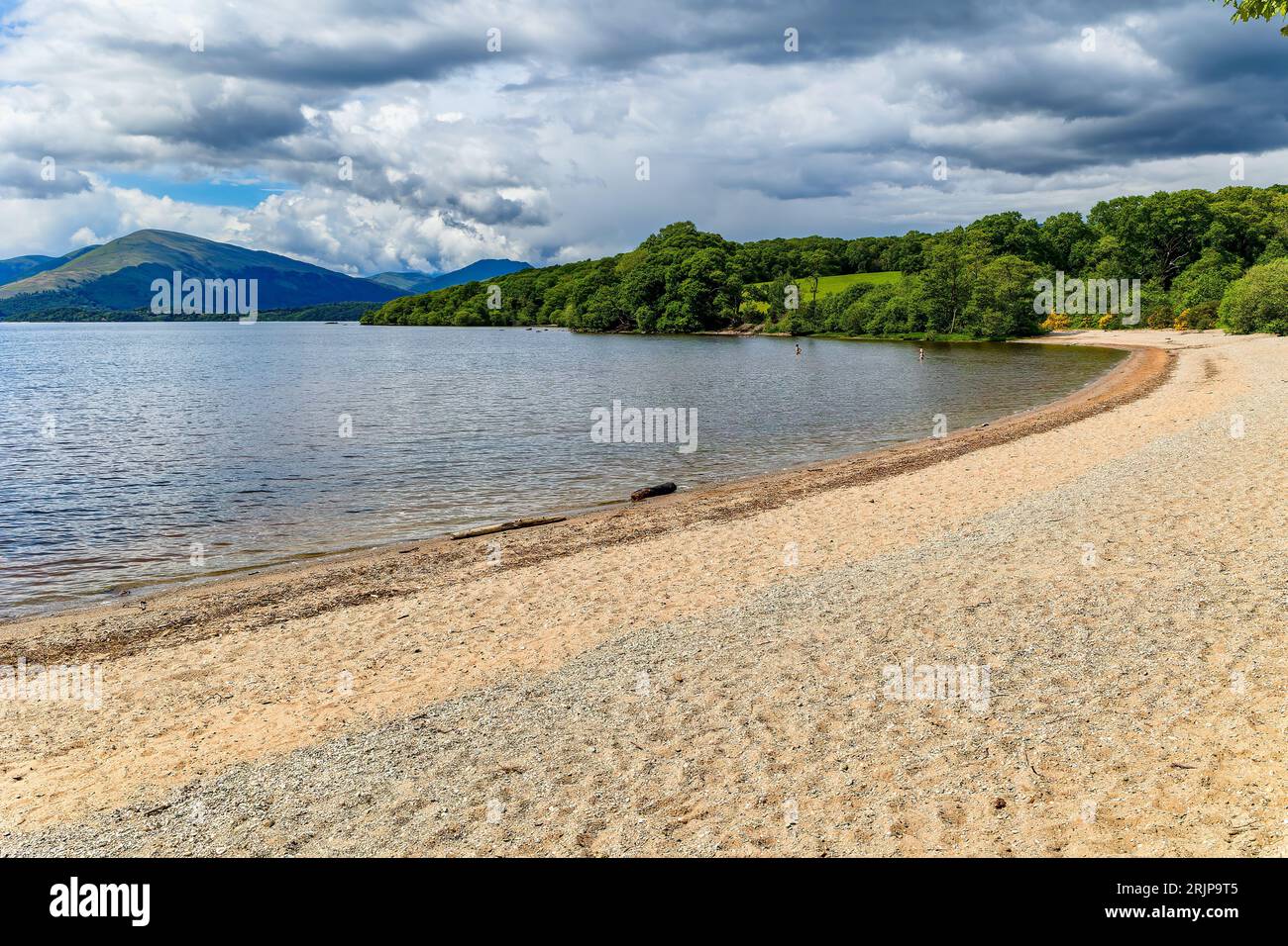 Belle plage sur les rives d'un grand lac d'eau douce entouré de montagnes (Loch Lomond, Écosse, UK) Banque D'Images