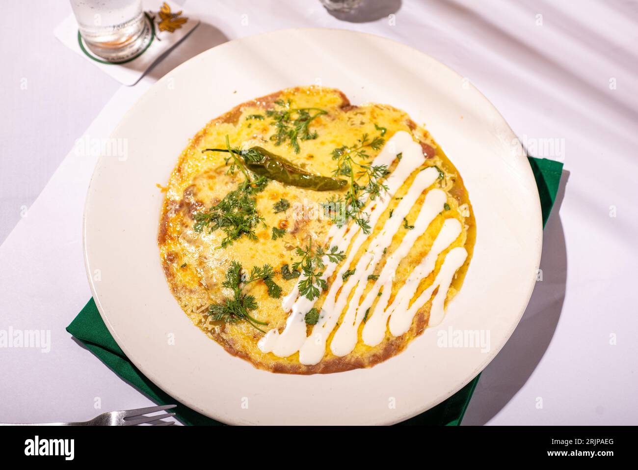 Une omelette appétissante avec des légumes frais et des herbes sur une assiette blanche, prête à être dégustée Banque D'Images