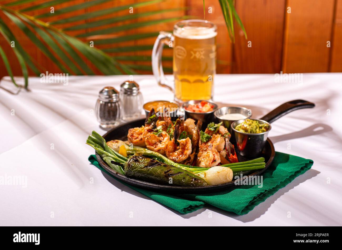 Un gros plan d'une assiette de légumes et de crevettes fraîchement cuits, avec un verre de bière en arrière-plan Banque D'Images