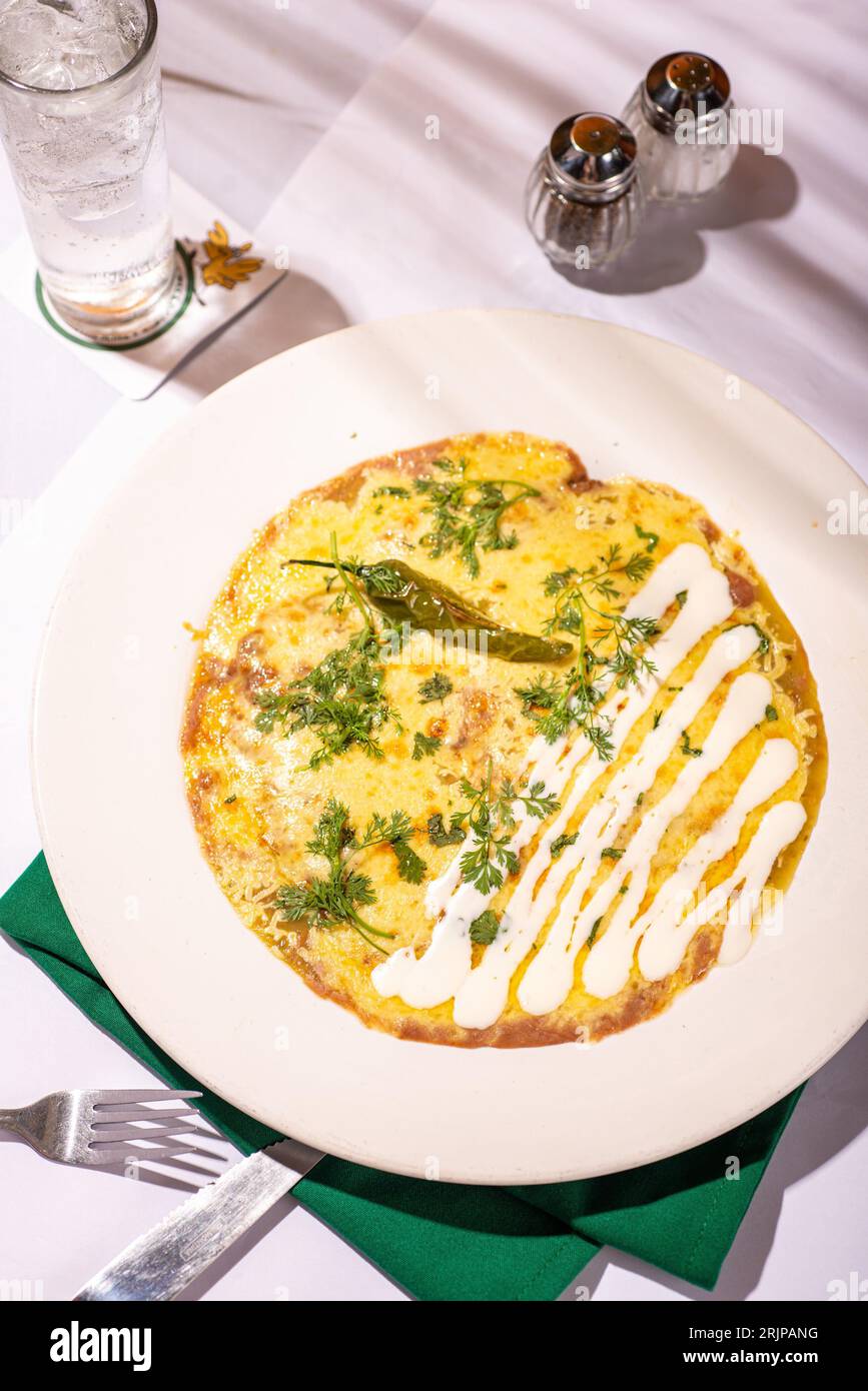 Une omelette appétissante avec des légumes frais et des herbes sur une assiette blanche, prête à être dégustée Banque D'Images
