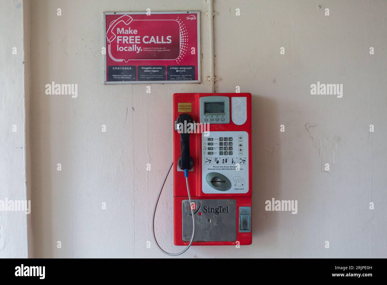 Une vue rare d'un téléphone public de couleur rouge sous un lotissement à Singapour. Banque D'Images