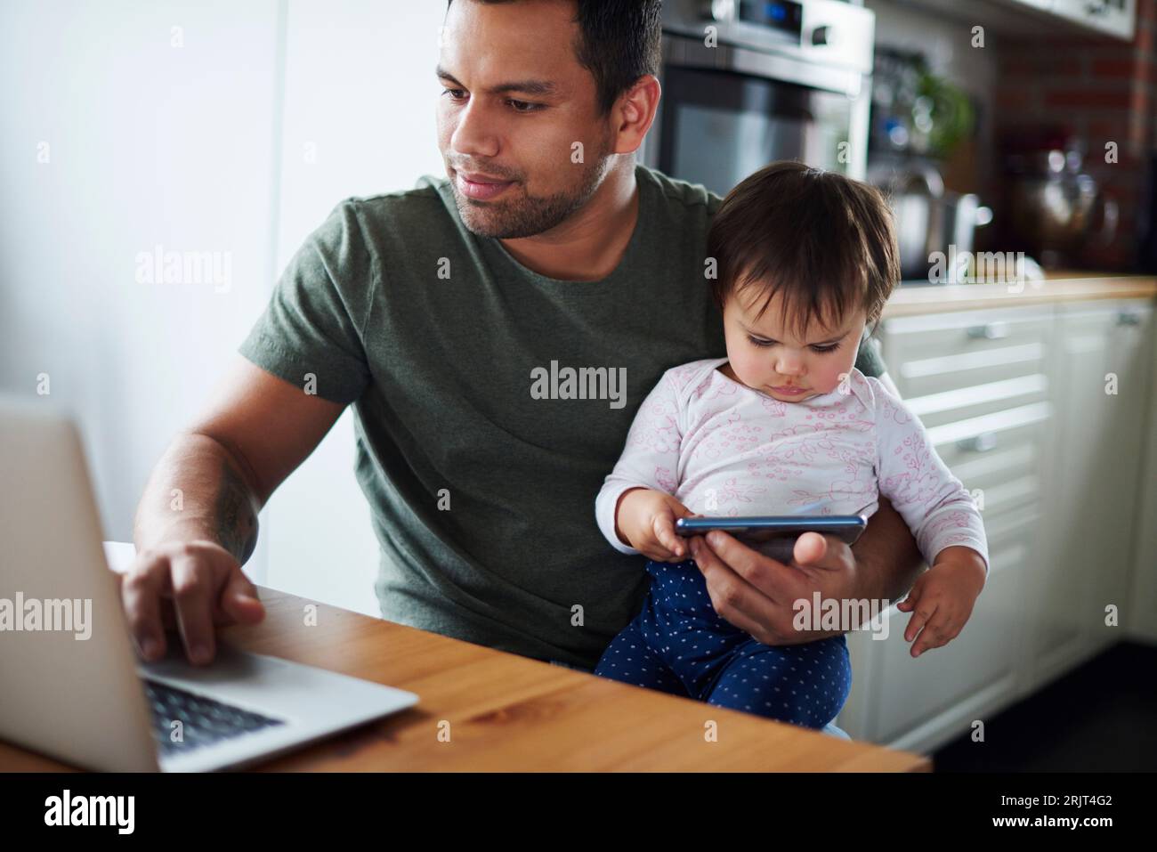 Père à l'aide d'un ordinateur portable avec une petite fille à l'aide d'un smartphone à la maison Banque D'Images