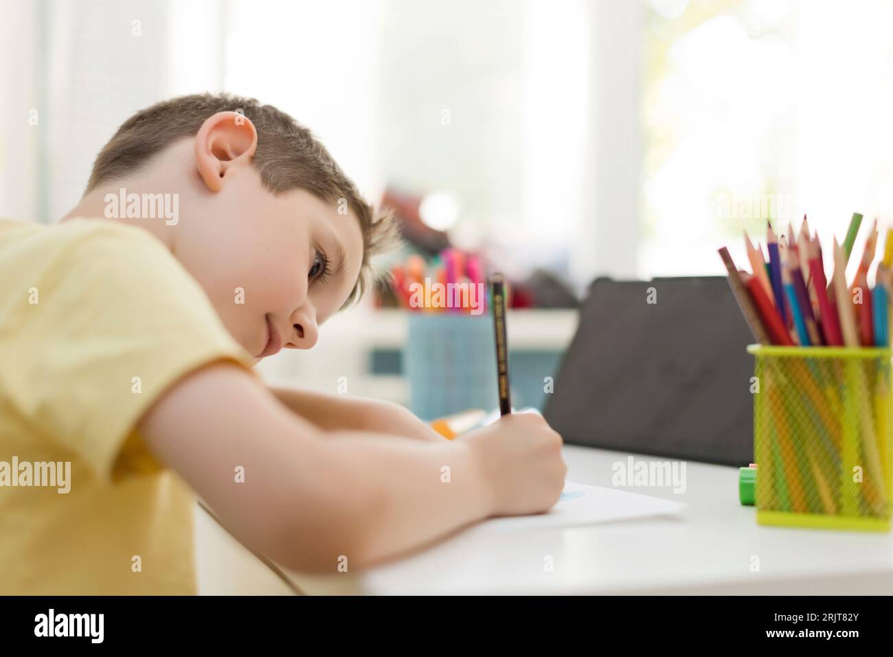 Garçon en concentration apprenant à dessiner avec un crayon de couleur à la maison Banque D'Images