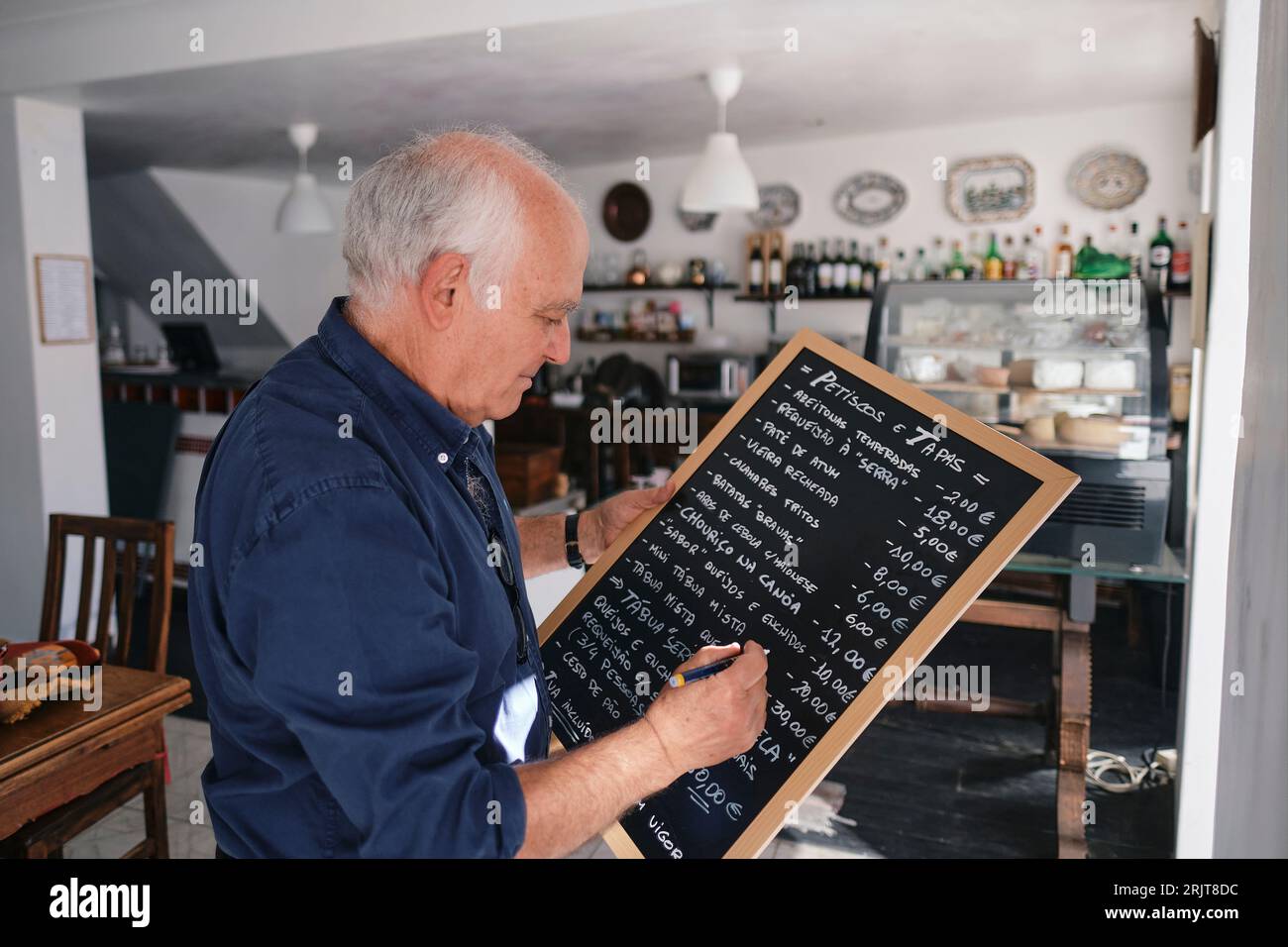 Propriétaire de café écrivant le menu sur le tableau noir avec stylo Banque D'Images