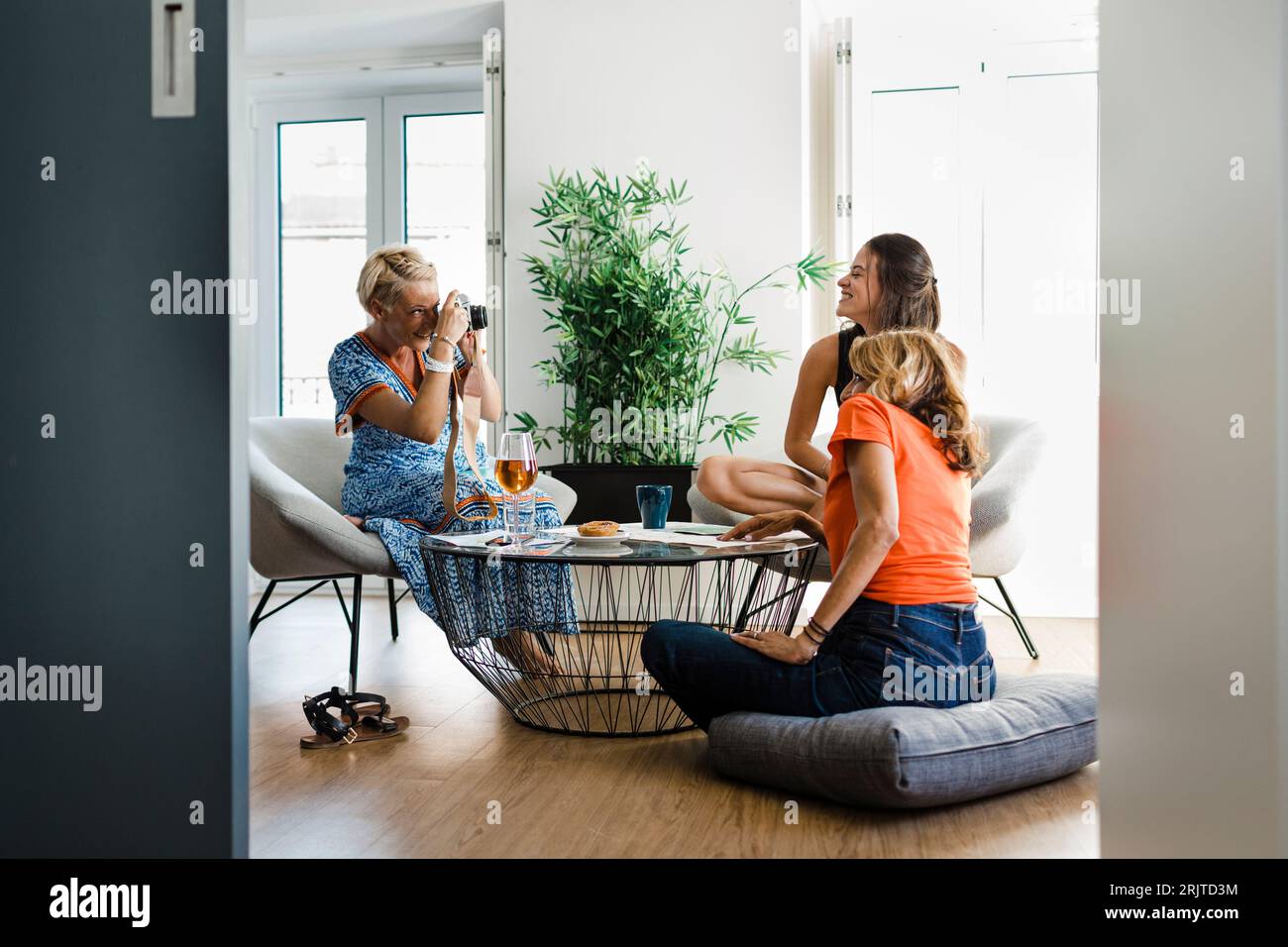 Femme heureuse photographiant des amis dans l'appartement Banque D'Images