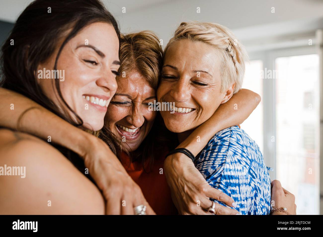 Amis joyeux s'embrassant dans l'appartement Banque D'Images