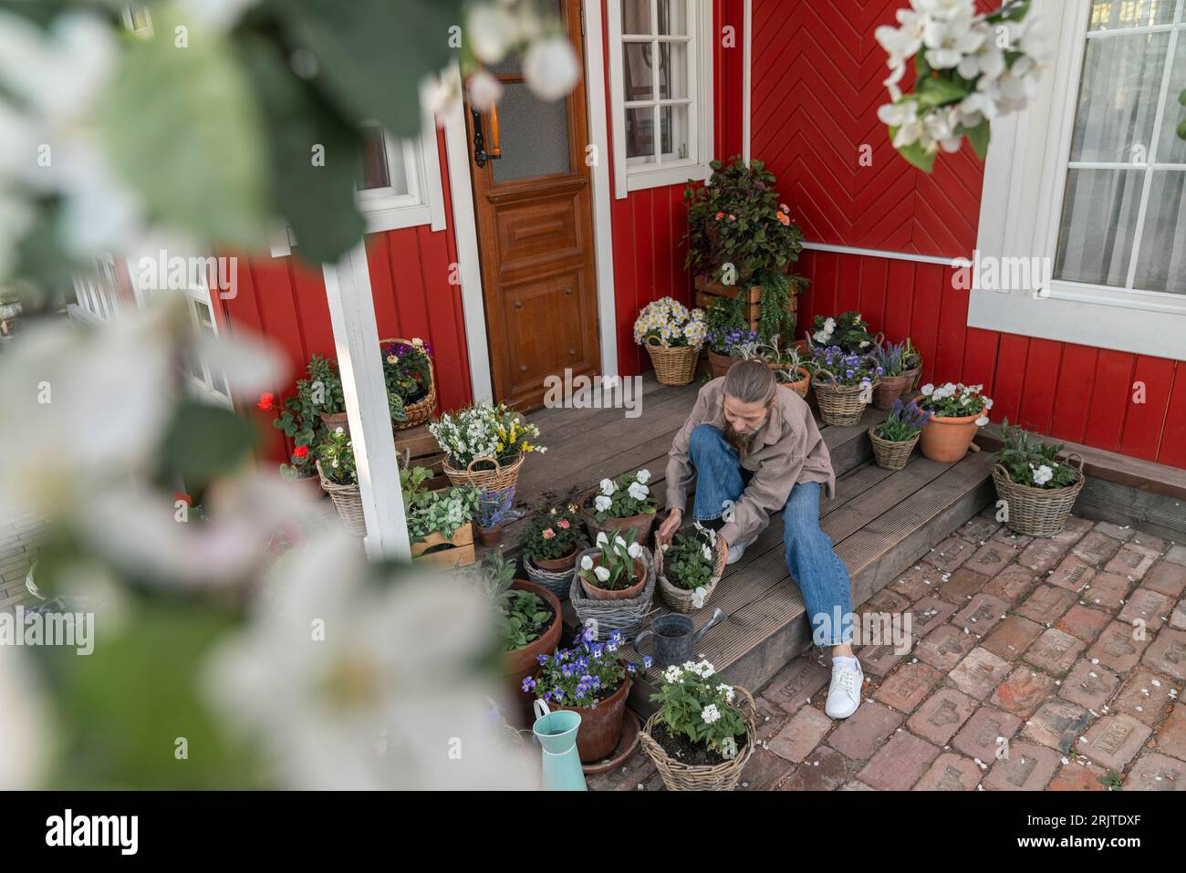 Femme arrangeant des plantes assis sur le porche Banque D'Images