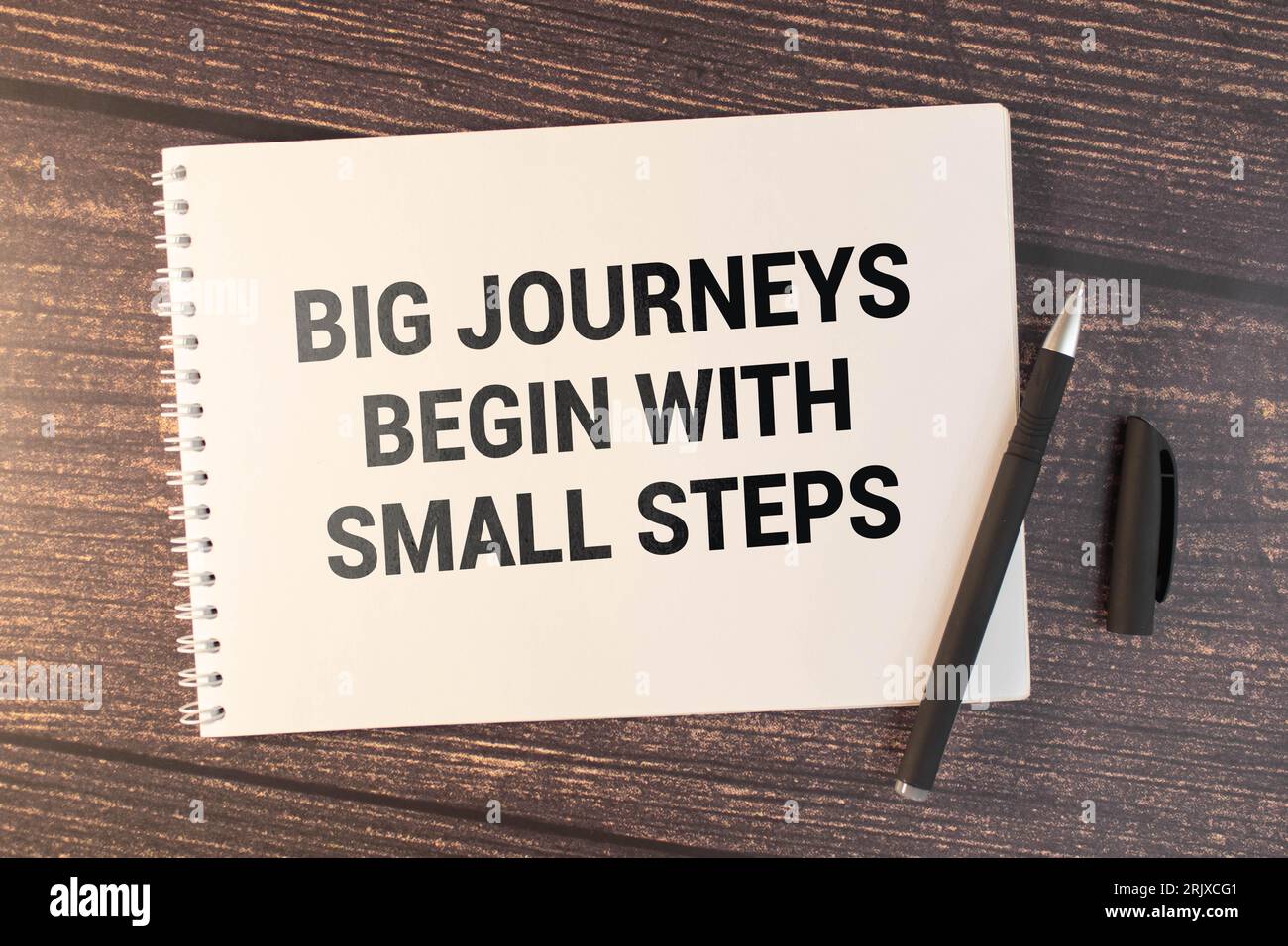 Concept commercial. Carnet de notes avec texte Grands voyages commencer par de petites étapes feuille de papier blanc pour les notes, calculatrice, lunettes, crayon, stylo, dans le whit Banque D'Images