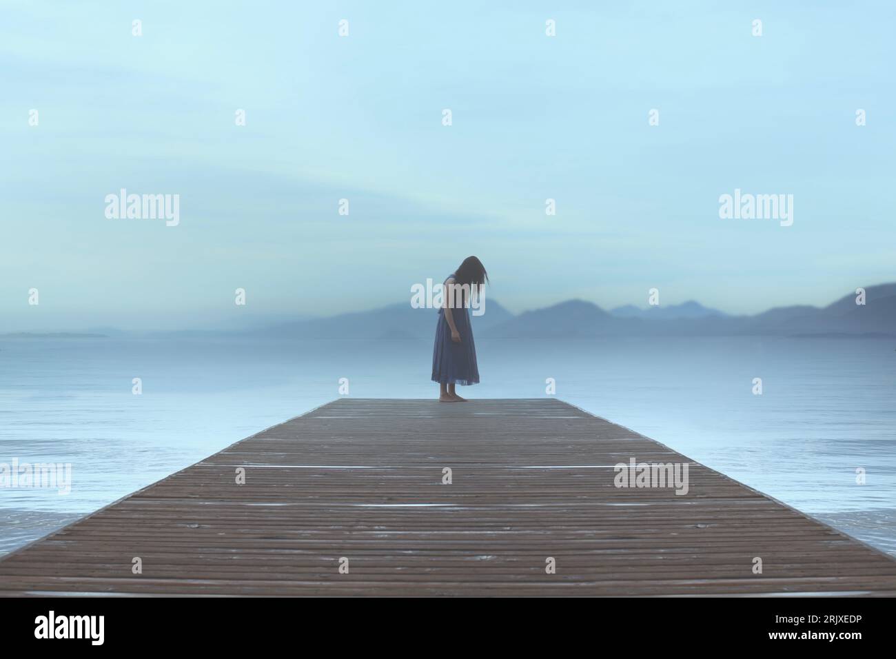 femme solitaire debout sur une jetée au bord de la mer est emporté par les émotions dans une atmosphère surréaliste bleue Banque D'Images