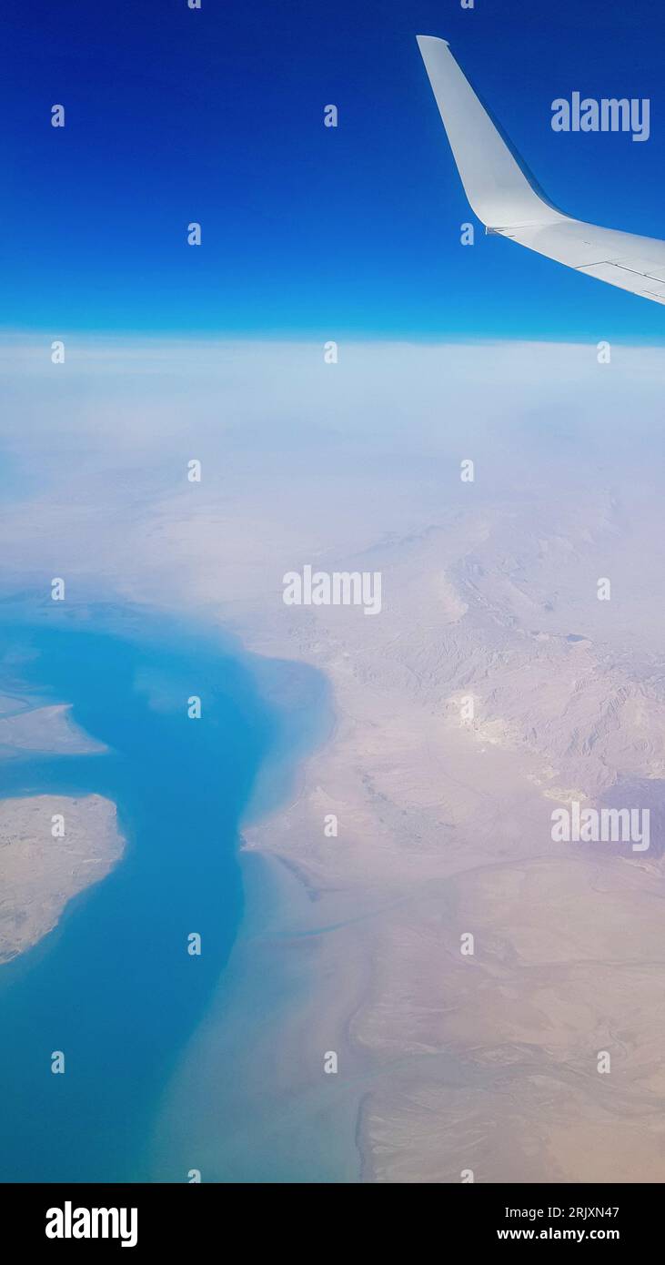 Vue de la fenêtre de l'avion sur le ciel bleu et la terre avec paysage de désert, mer et canaux dans les Émirats. Photo de haute qualité Banque D'Images