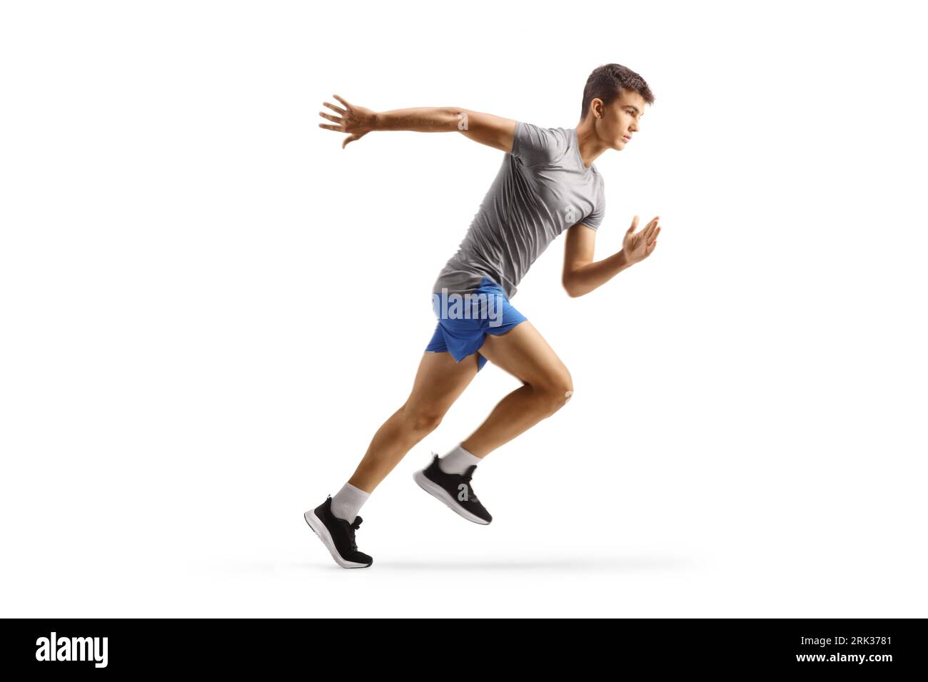 Photo de profil pleine longueur d'un adolescent masculin en forme en cours d'exécution isolé sur fond blanc Banque D'Images