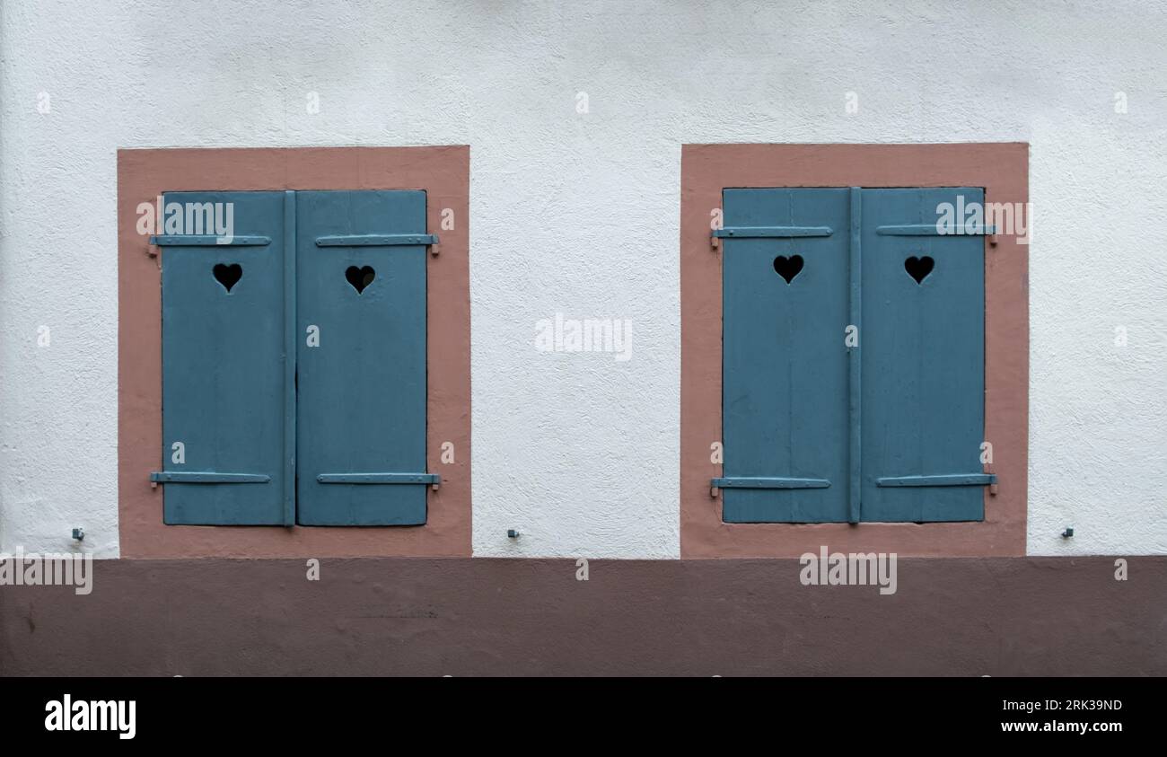 Fenêtres avec volets en bois fermés bleus sur fond de mur en pierre blanche. Obturateur avec trou de coeur, symbole d'amour. Banque D'Images
