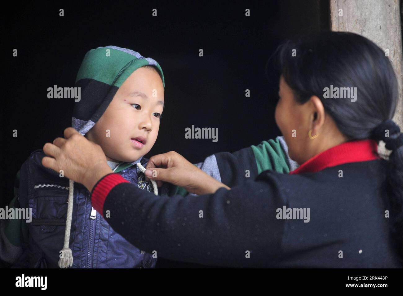 Bildnummer : 53585252 Datum : 12.10.2009 Copyright : imago/Xinhua (091108) -- ENSHI, 8 novembre 2009 (Xinhua) -- Yang Xiulin (R), grand-mère de Zhu Xu, habille Zhu avant d'aller à l'école dans le comté de Xianfeng à Enshi, province du Hubei en Chine centrale, 12 octobre 2009. Zhu Xu, âgé de huit ans, était élève de 3e année de l'école primaire Boyangping Nationality. Un enfant comme lui était censé vivre heureux avec ses parents, mais dans sa mémoire, il n'avait pas un tel bonheur. Son père Zhu Gang avait quitté la maison pour chercher du travail depuis 1994. En 2001, après la naissance de Zhu Xu, sa mère se rend également dans le sud-ouest de la Chine Banque D'Images