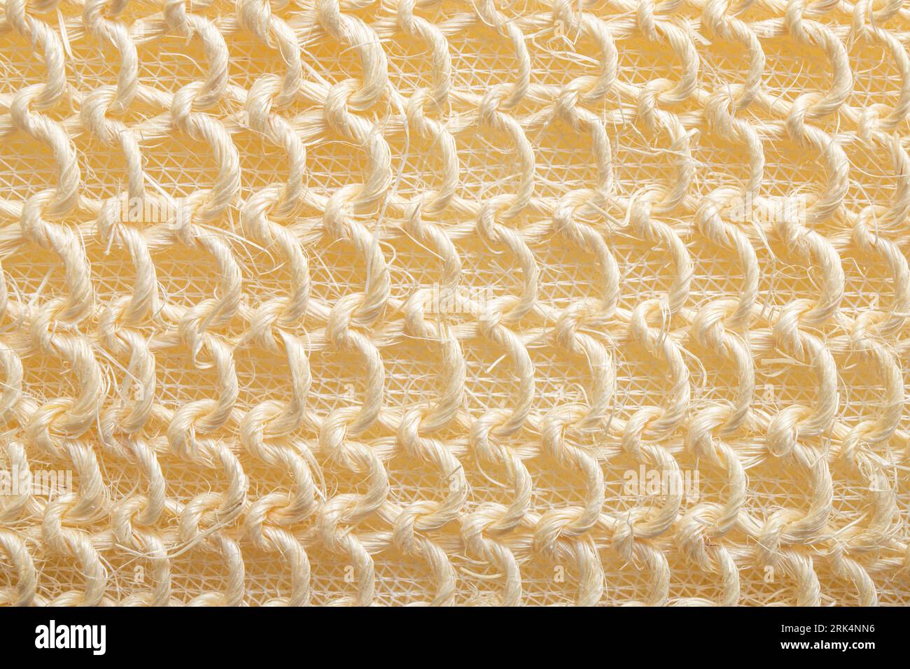 Vue rapprochée de la texture de l'éponge de bain tressée. Texture de couleur pastel beige. Banque D'Images