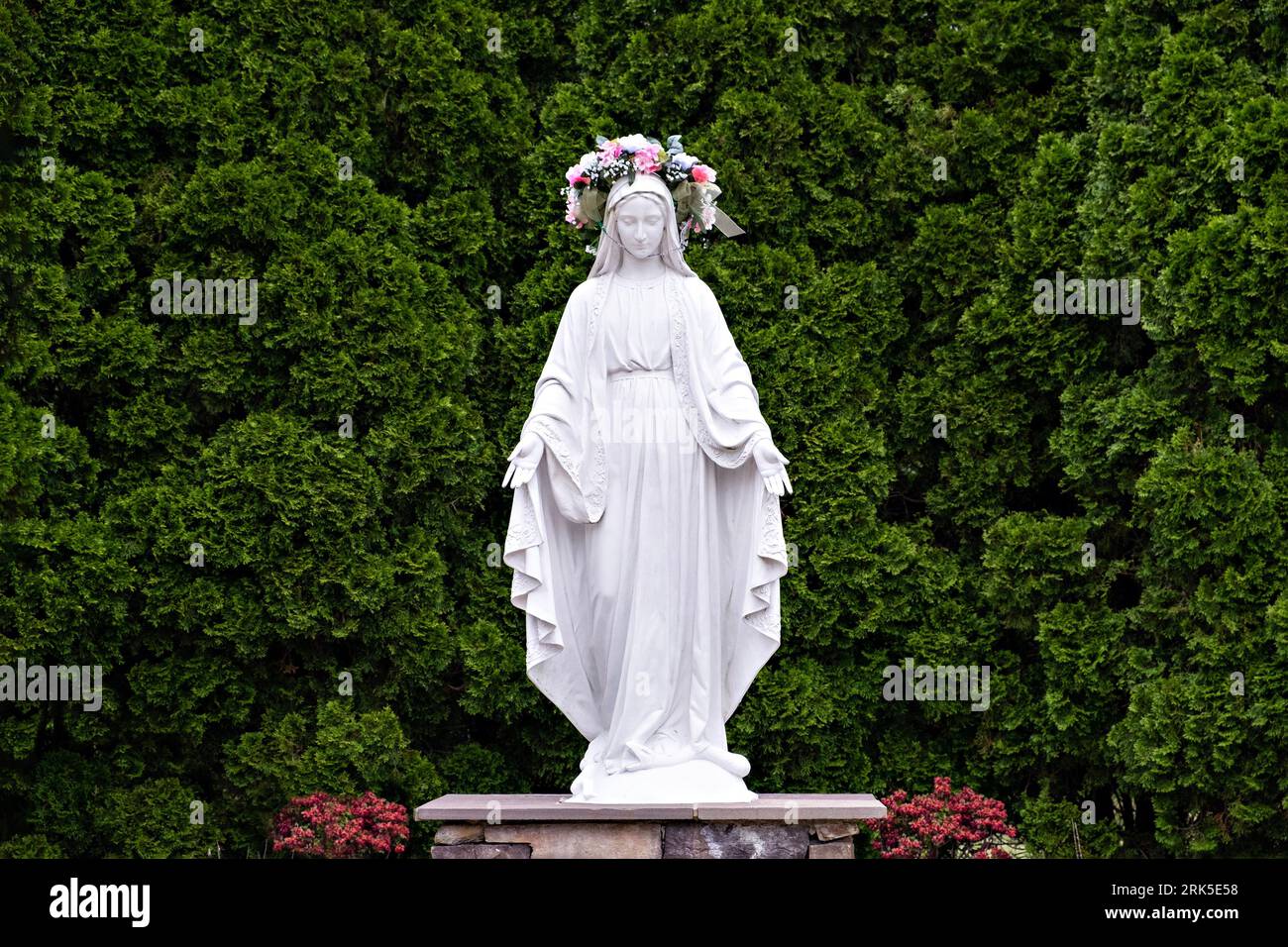 Une statue en marbre blanc représentant une figure féminine se dresse dans un parc entouré d'arbres verdoyants Banque D'Images