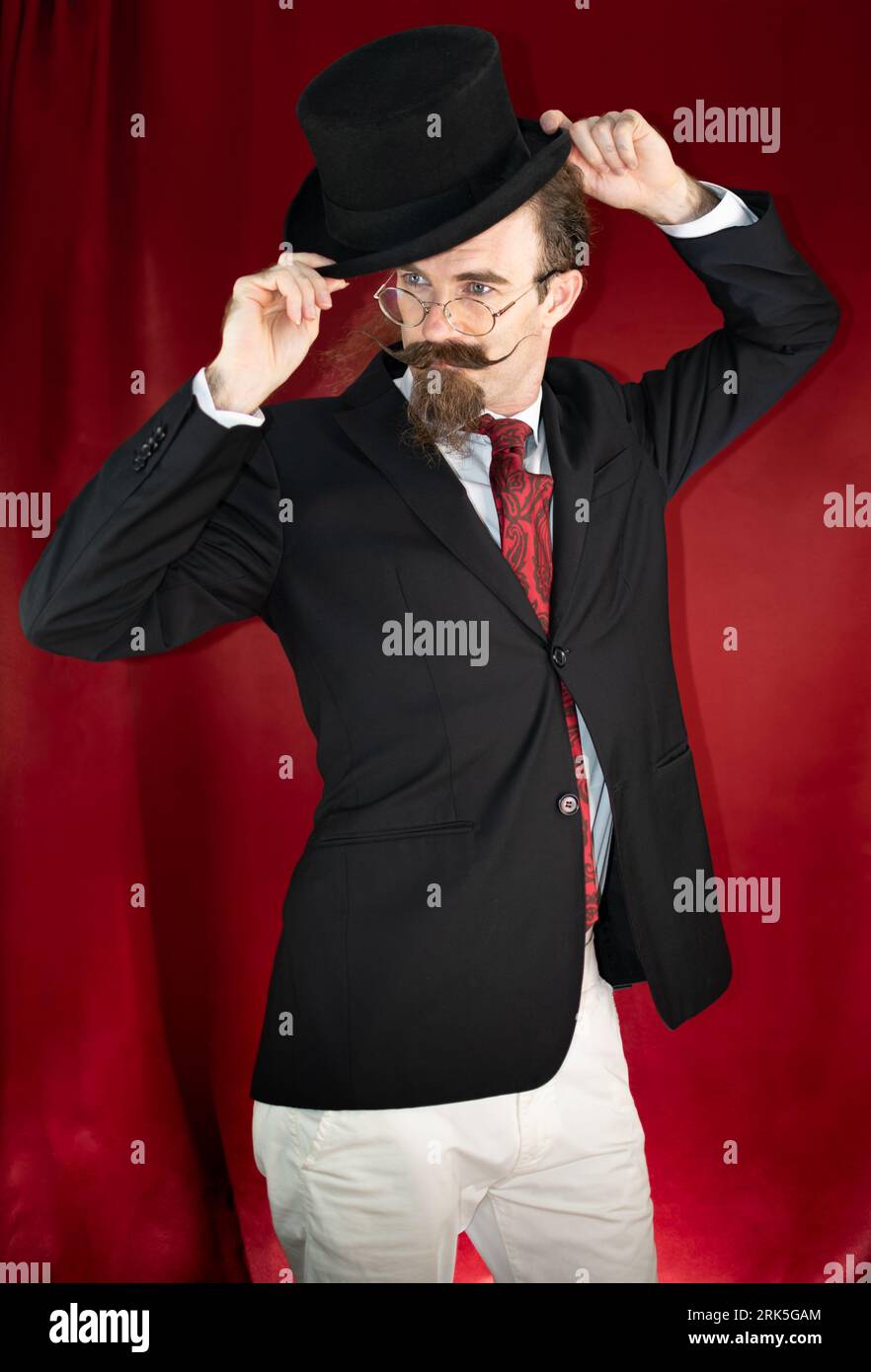 Magicien caucasien vintage avec chapeau haut de gamme, lunettes et moustache posant Banque D'Images