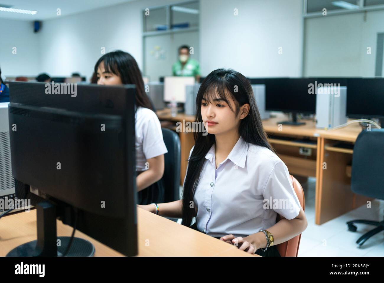 Une étudiante asiatique travaille sur un ordinateur portable dans une salle d'étude Banque D'Images