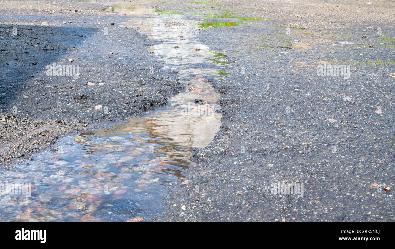 mousse savonneuse blanche dans l'eau sale dans une flaque d'eau sur la route Banque D'Images