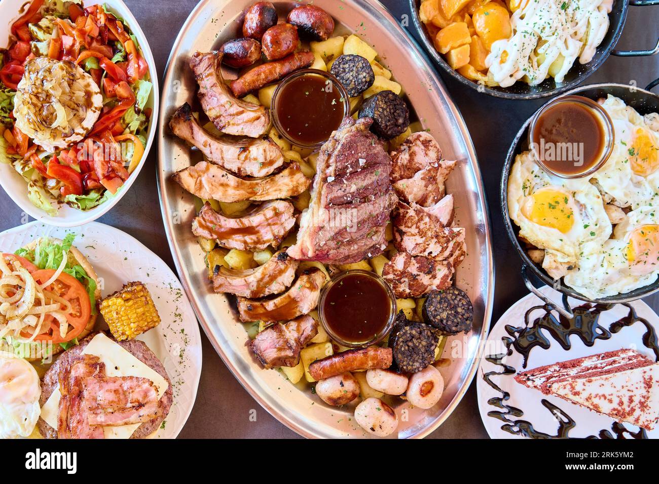 Une variété de plats espagnols avec des côtes levées au barbecue, des œufs au plat et des pommes de terre agrémentées de sauces habilement disposées sur une assiette Banque D'Images