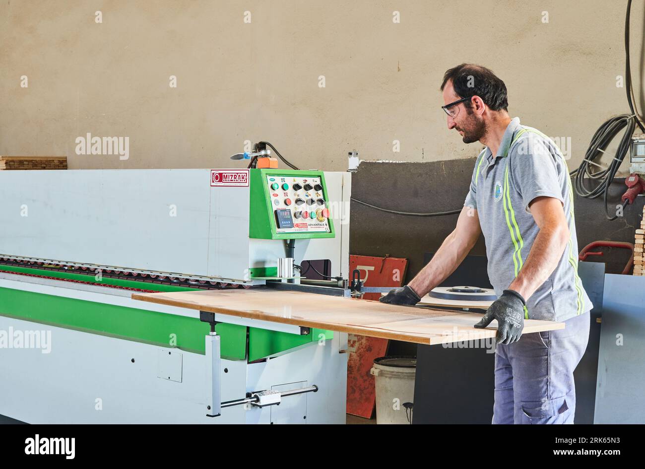 menuisier travaillant sur le bois dans un atelier. travailleur masculin avec un masque et un gilet de sécurité. menuiserie Banque D'Images