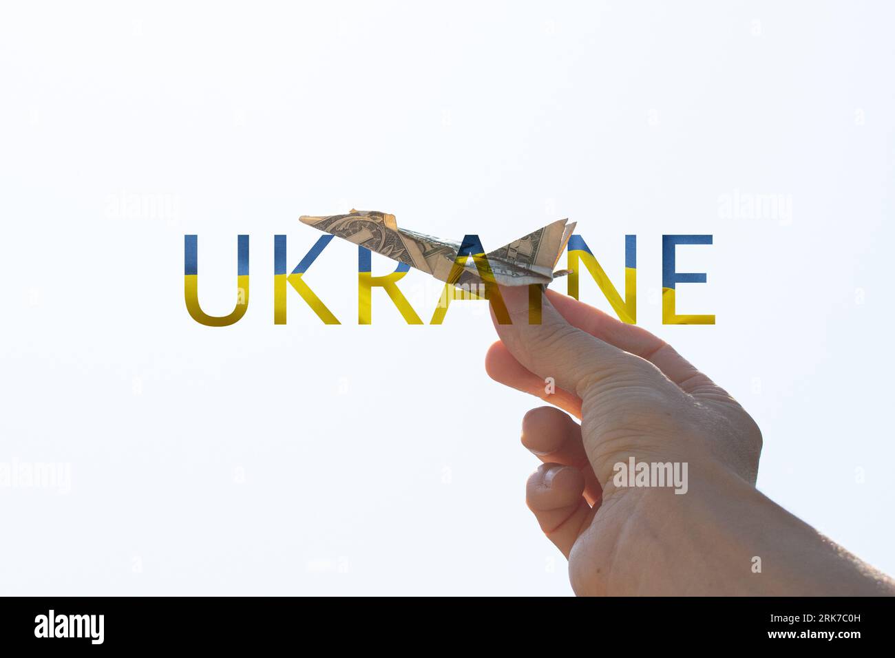 Avion d'un dollar dans la main d'une fille dans le ciel au-dessus de l'Ukraine et l'avion vole à travers le mot Ukraine dans le ciel, la liberté et la vie Banque D'Images
