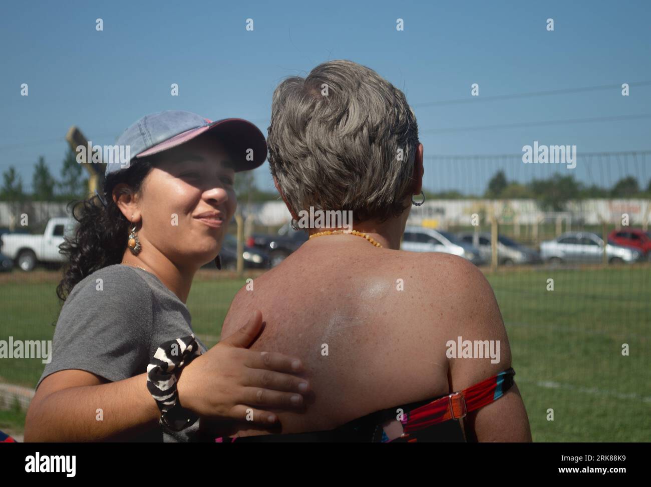 Jeune femme passant de la crème solaire sur le dos de sa belle-mère pendant un match de football. Banque D'Images