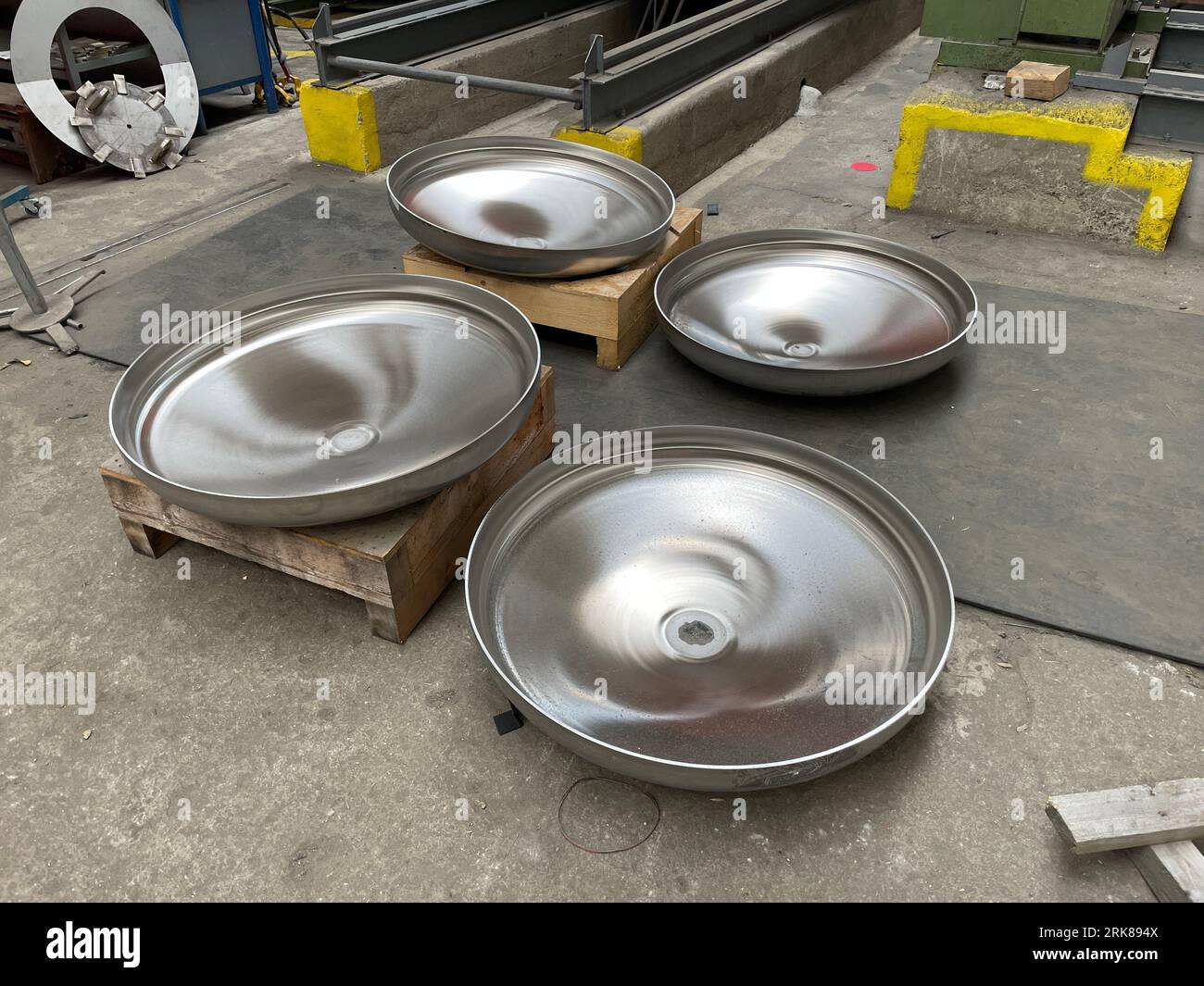 Un gros plan de quatre bols en acier inoxydable, avec divers autres objets métalliques et équipements dispersés autour Banque D'Images