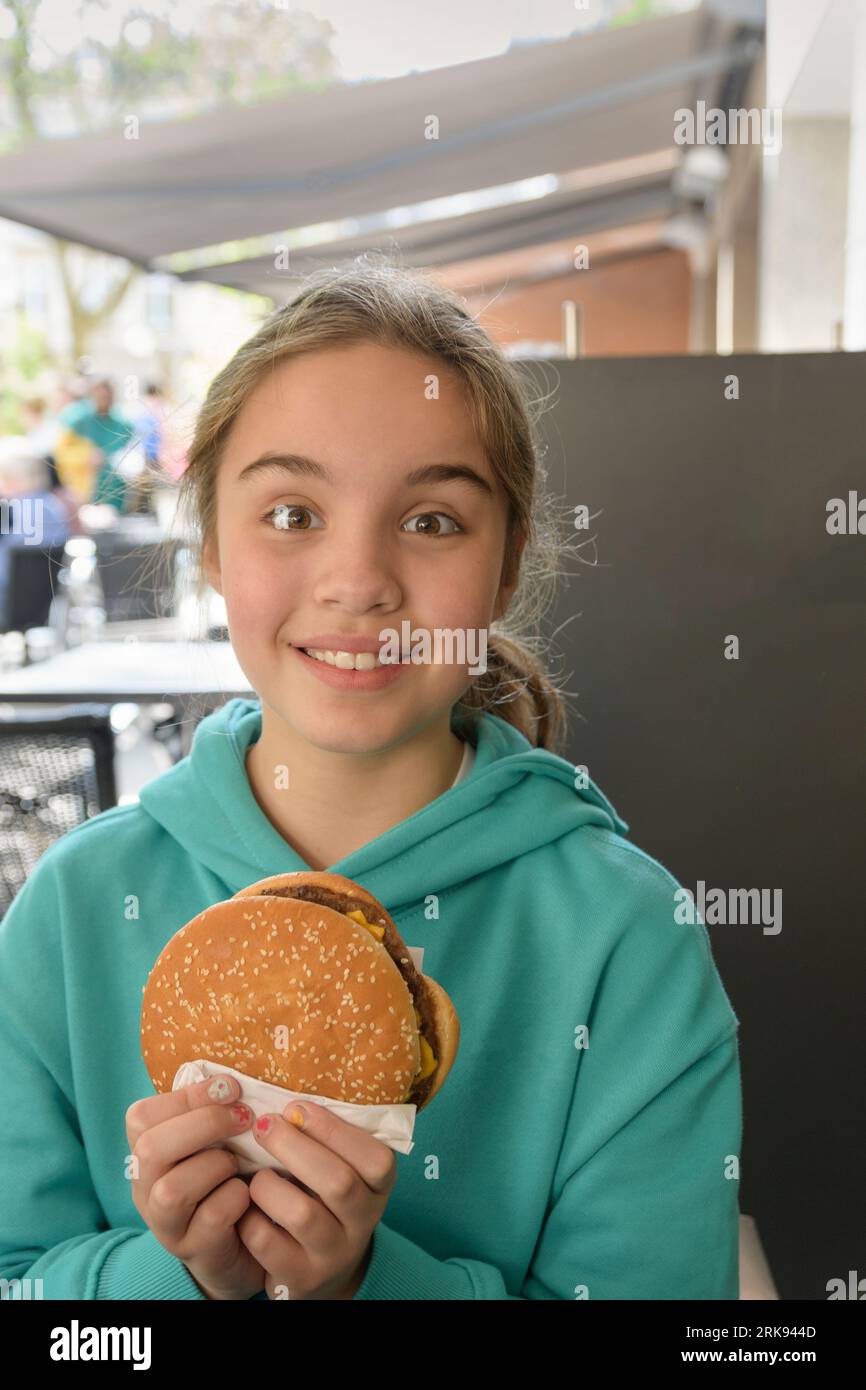 Fille dans un café avec un grand hamburger. Restauration rapide, mode de vie. Portrait gros plan. Placer pour le texte Banque D'Images