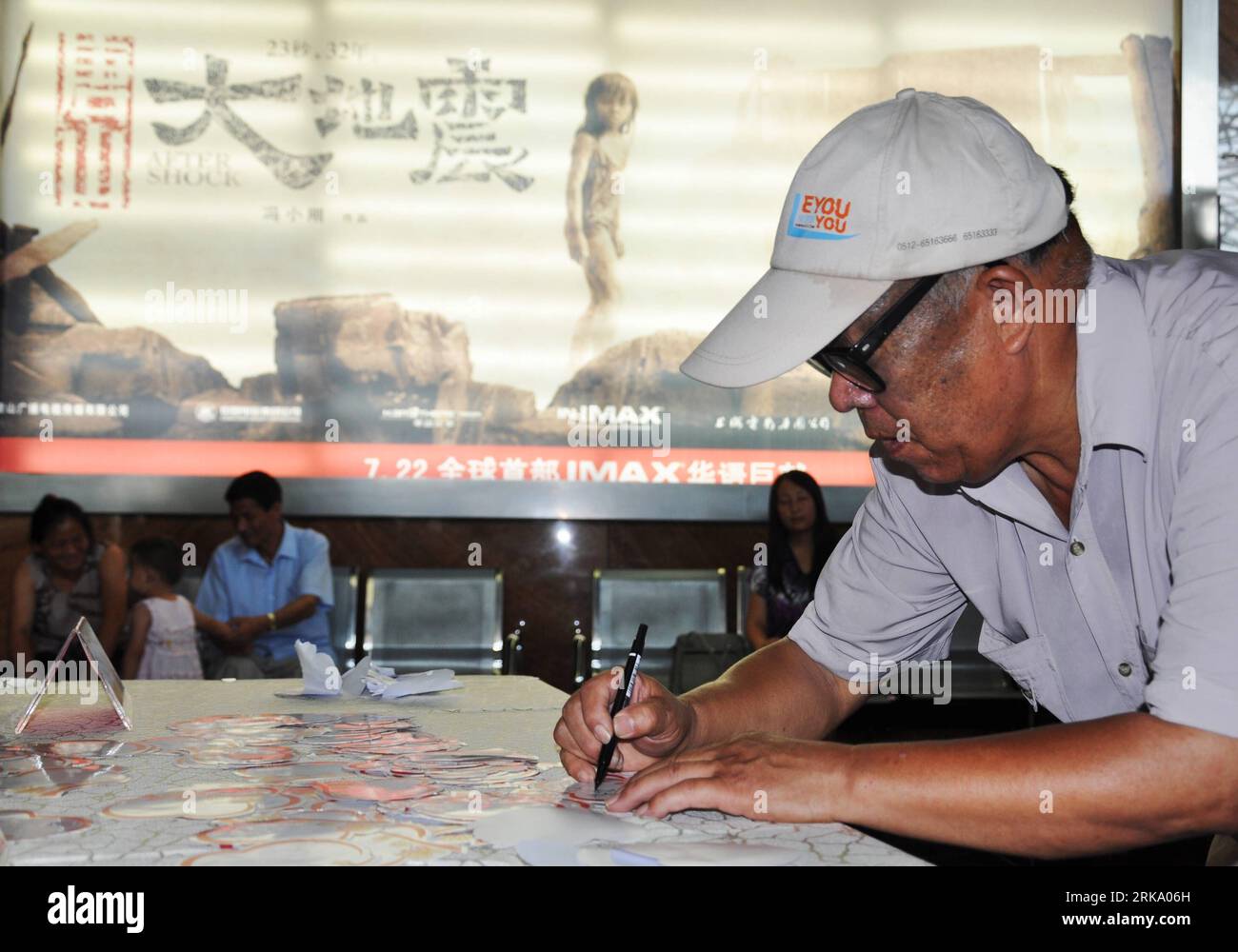 Bildnummer : 54248548 Datum : 22.07.2010 Copyright : imago/Xinhua (100723) -- SUZHOU, 23 juillet 2010 (Xinhua) -- Zhang Hong, un survivant de 62 ans du tremblement de terre de Tangshan, écrit ses vœux sur un journal lors d'une première du film Aftershock à Suzhou, dans la province du Jiangsu, dans l'est de la Chine, le 22 juillet 2010. En 1976, un séisme de magnitude 7,8 a frappé la ville de Tangshan, dans la province du Hebei, au nord de la Chine, et a fait plus de 240 000 morts. Le film Aftershock qui est réalisé par , reflète le tremblement de terre dévastateur à Tangshan en 1976. Le film, avec le slogan 23 secondes, 32 ans, raconte l'histoire d'une mère qui ha Banque D'Images