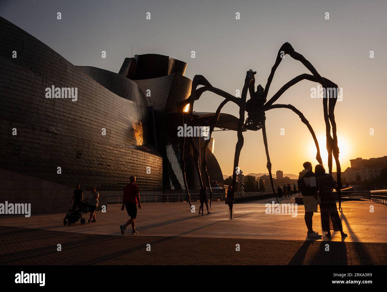 Bilbao, Espagne - 02 août 2022: Quelques touristes prennent un selfie au coucher du soleil à côté de l'araignée, la sculpture de Louise Bourgeois intitulée Mamam in Th Banque D'Images