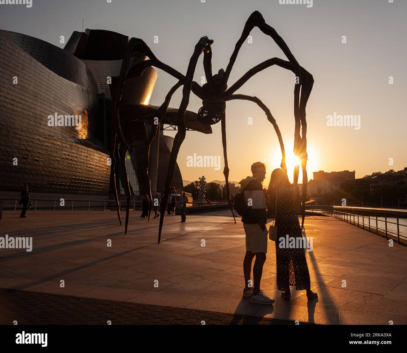 Bilbao, Espagne - 02 août 2022: Quelques touristes prennent un selfie au coucher du soleil à côté de l'araignée, la sculpture de Louise Bourgeois intitulée Mamam in Th Banque D'Images