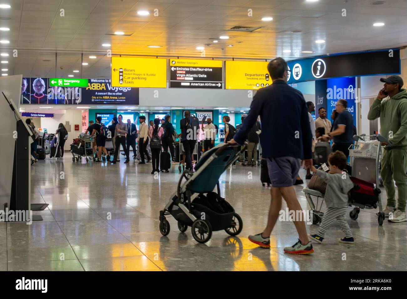 Des panneaux jaunes suspendus au plafond indiquent aux passagers les indications à l'arrivée du terminal 3 de l'aéroport de Londres Heathrow Banque D'Images