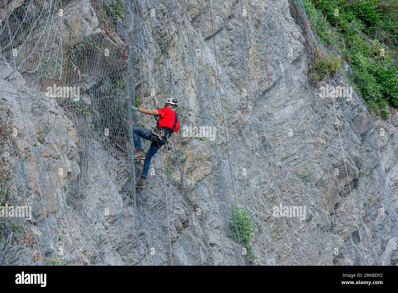 Dossena Italie 24 août 2023 : Climber pose des filets de sécurité pour éviter les chutes de pierres Banque D'Images