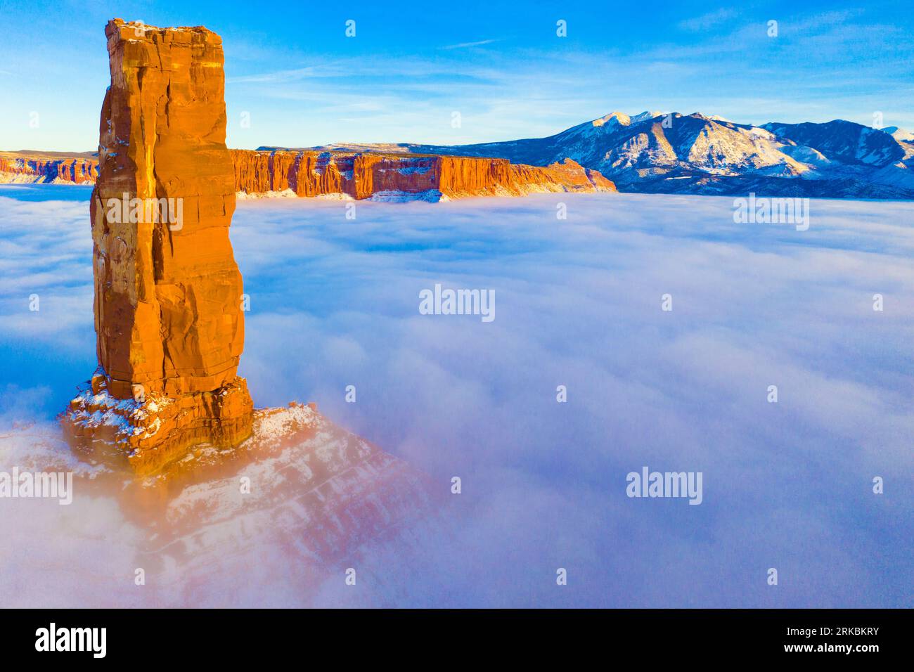 Castle Rock s'élève au-dessus du brouillard hivernal, Castle Vallery Utah, près de Moab, Coloraod River, Une «gloire» de la lumière du soleil sur le brouillard apparaît, Lqa Sal montagnes au-delà Banque D'Images