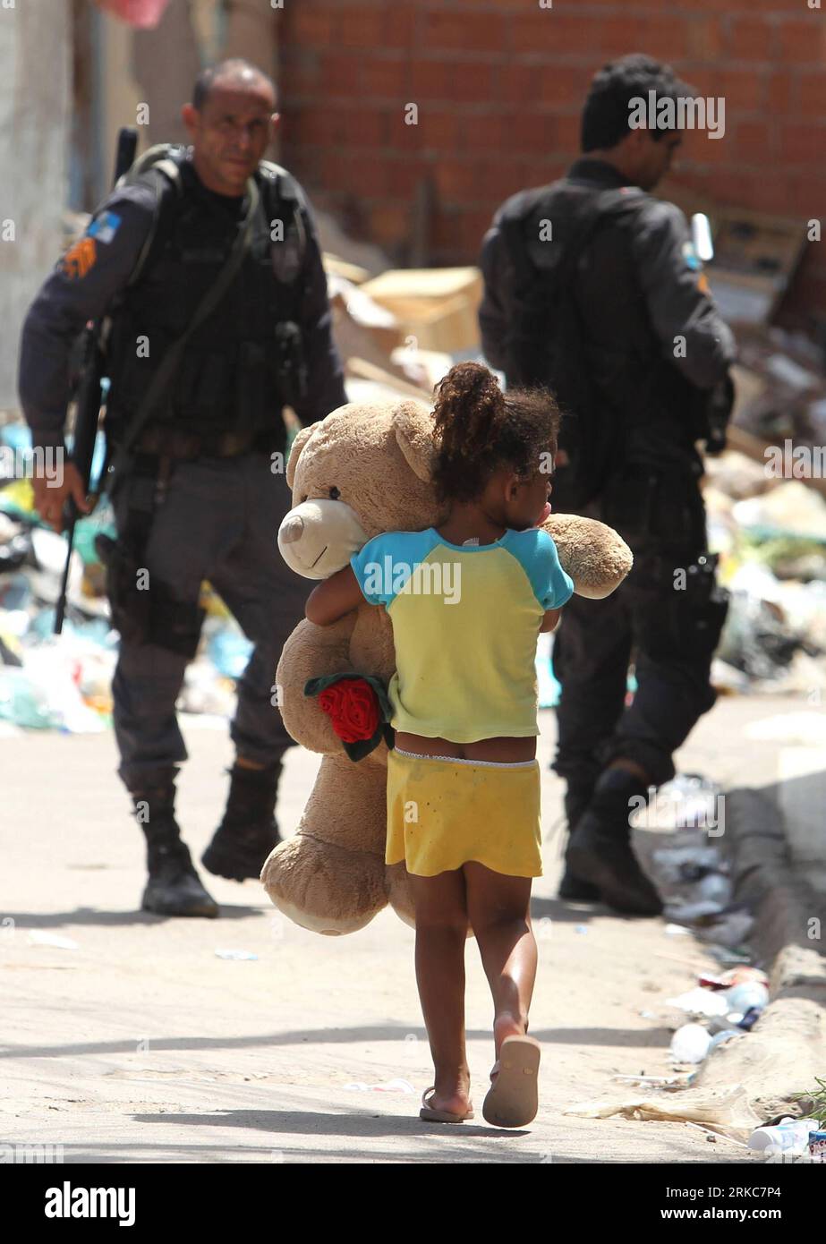 Bildnummer : 54688359 Datum : 29.11.2010 Copyright : imago/Xinhua (101130) -- RIO DE JANERIO, 30 novembre 2010 (Xinhua) -- Une enfant porte son ours en peluche alors qu'elle marche à côté de soldats, dans le bidonville d'Alemao, Rio de Janeiro, Brésil, le 29 novembre 2010. Le bidonville d'Alemao a été le deuxième à être repris par la police, où elle a arrêté des membres de gangs et saisi de grandes quantités de drogue et d'armes. (Xinhua/Agencia Estado)(BRAZIL OUT)(axy) BRAZIL-RIO DE JANERIO-VIOLENCE PUBLICATIONxNOTxINxCHN Gesellschaft Polizei Favela Razzia Kampf gegen Drogen BRA Drogenkampf kbdig xsk 2010 hoch Highlight premiumd o0 Militär, Spez Banque D'Images