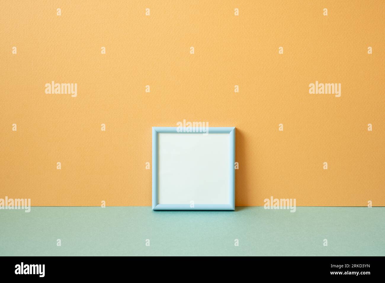 Cadre photo vide bleu sur la table vert menthe. fond de mur orange. espace de copie Banque D'Images