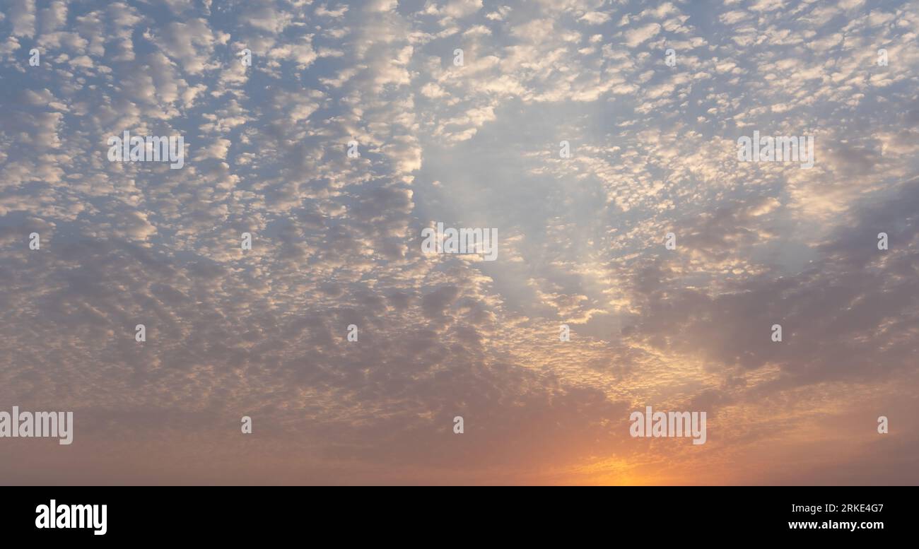 Une photo captivante capture le ciel serein du soir tandis que le soleil descendant baigne le monde d'une lueur chaude et dorée. Les teintes du ciel dépeignent à couper le souffle Banque D'Images