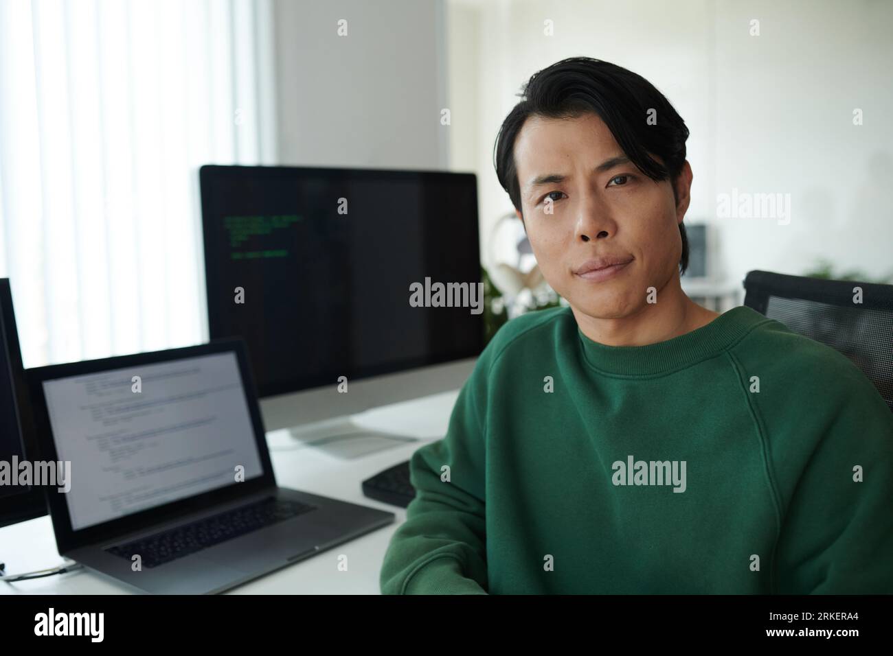 Portrait d'un développeur de logiciels asiatique sérieux assis à son bureau Banque D'Images
