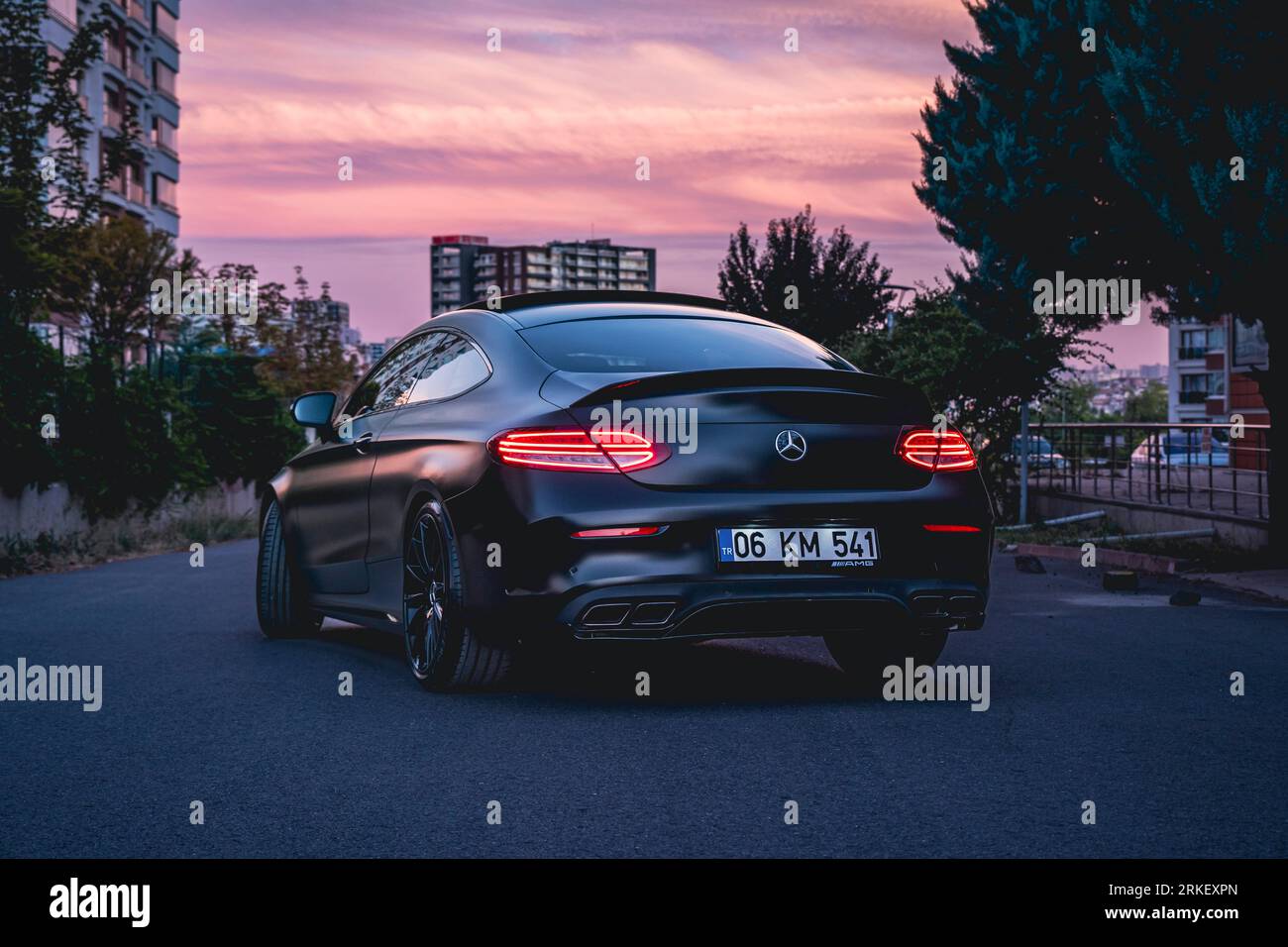 Noir Mercedes Benz C63s AMG au coucher du soleil de la ville. Banque D'Images