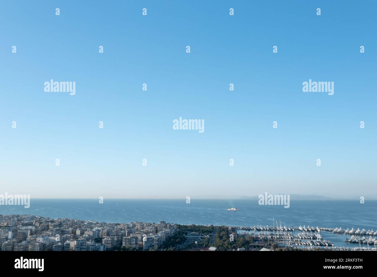 Athens Seaside Vista : maisons urbaines et navire solitaire sur les eaux calmes Banque D'Images